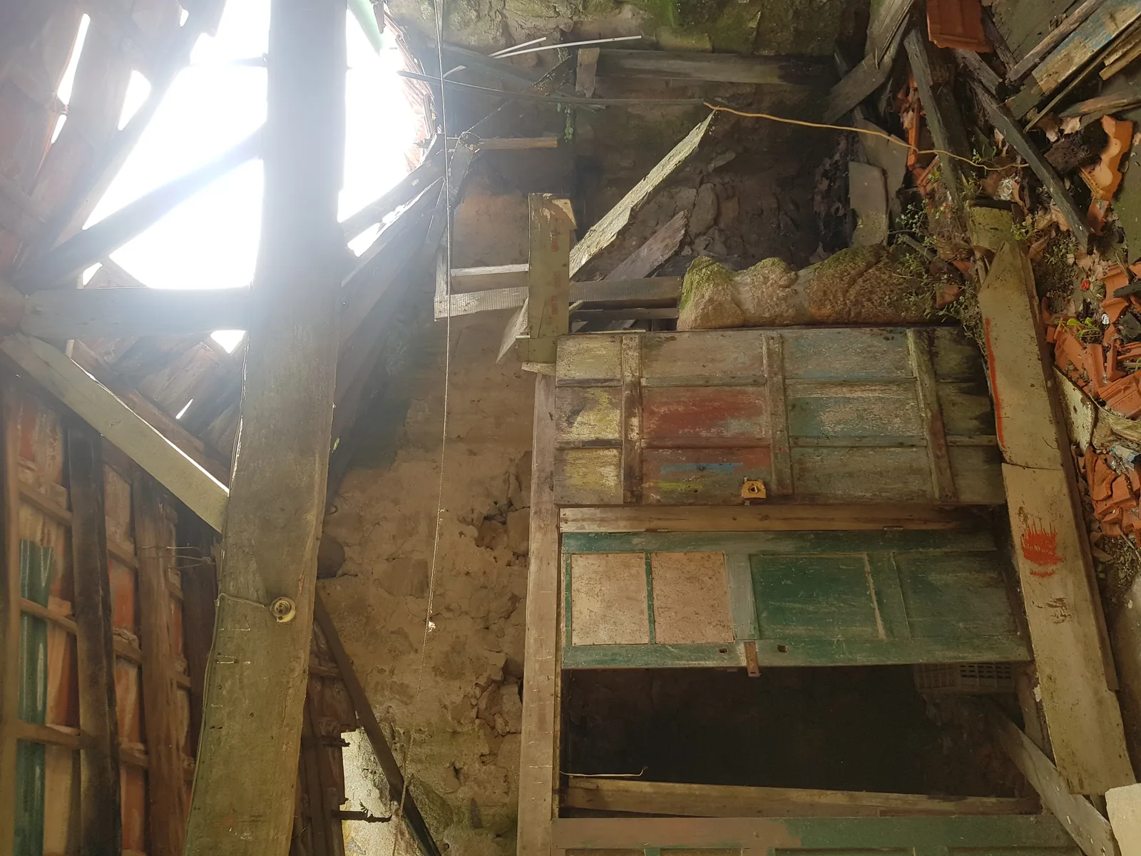 Before: DSLR street facade photo of existing granite ruin building in Canidelo showing full two-storey structure with ochre-yellow rendered walls, terracotta tiled roof, and deteriorated stone masonry
