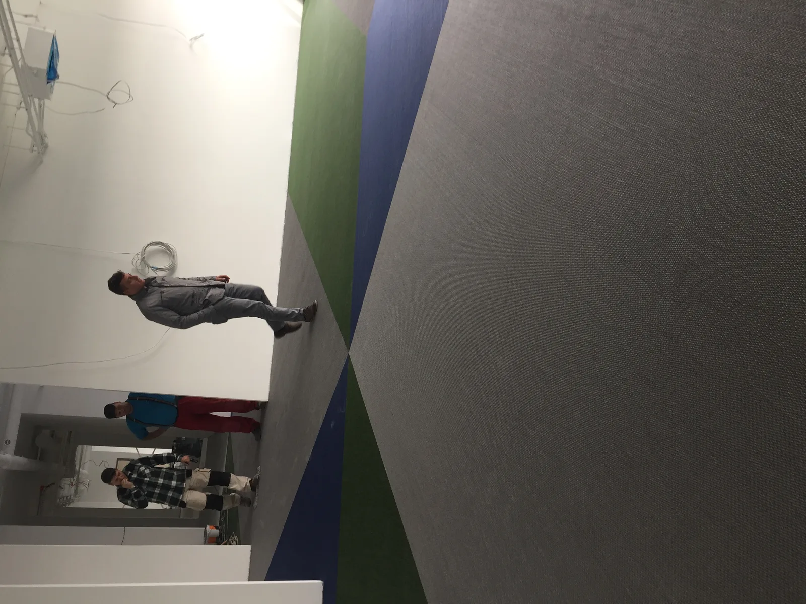 Workers installing the woven vinyl flooring with the oversized CETOR logo pattern, documenting the signature design element during the construction phase