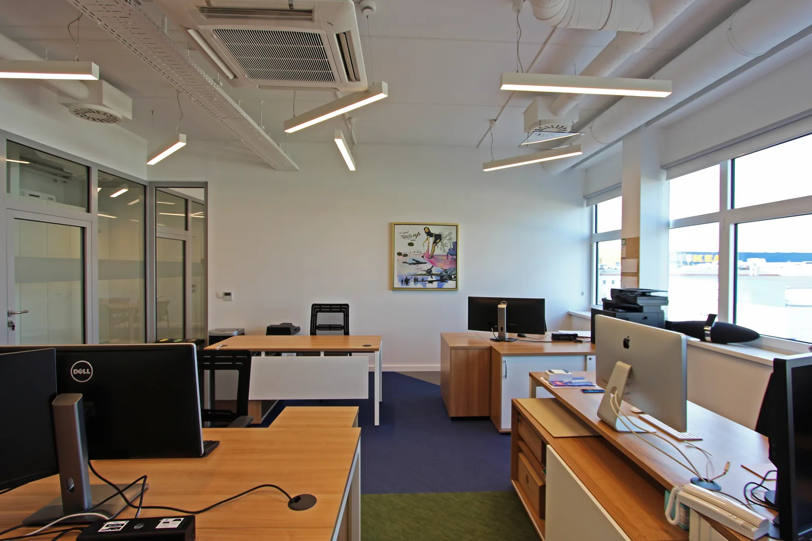 Conference room with long boardroom table, ceiling-mounted projector, framed certificates gallery wall, and woven vinyl floor