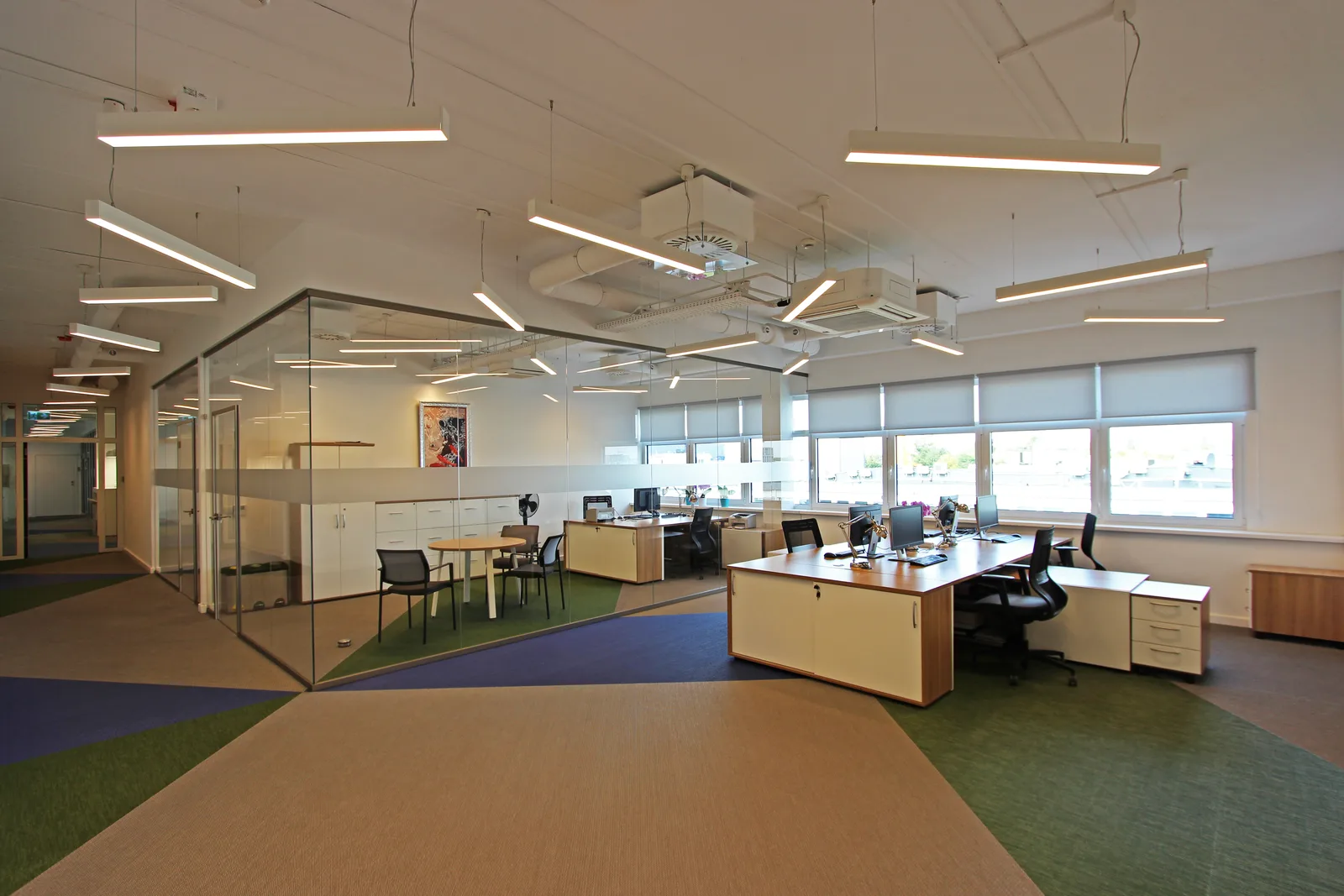 Open-plan office workspace showing the signature woven vinyl floor with the oversized CETOR cube logo pattern in beige, sage green, and navy blue