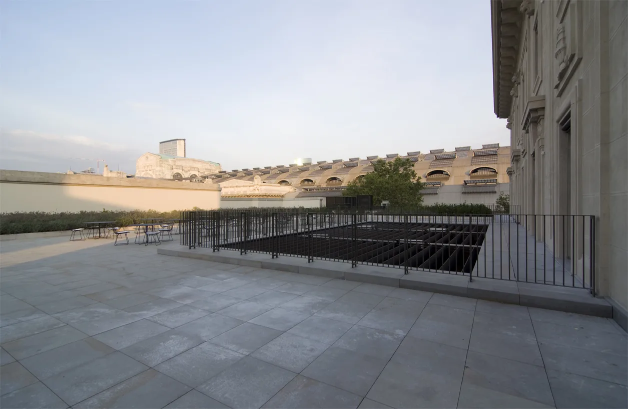 Terrace corner detail with the stone facade, parasol arrangement, and Milan urban context