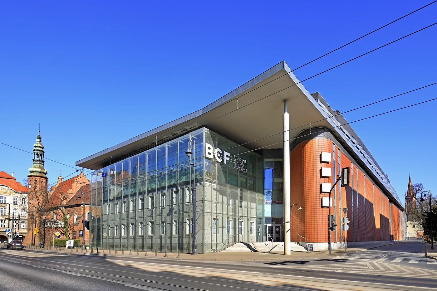 Exterior: professional photograph of Drukarnia Mall entrance zone and street-level commercial facade with new branding identity visible from Jagiellonska street