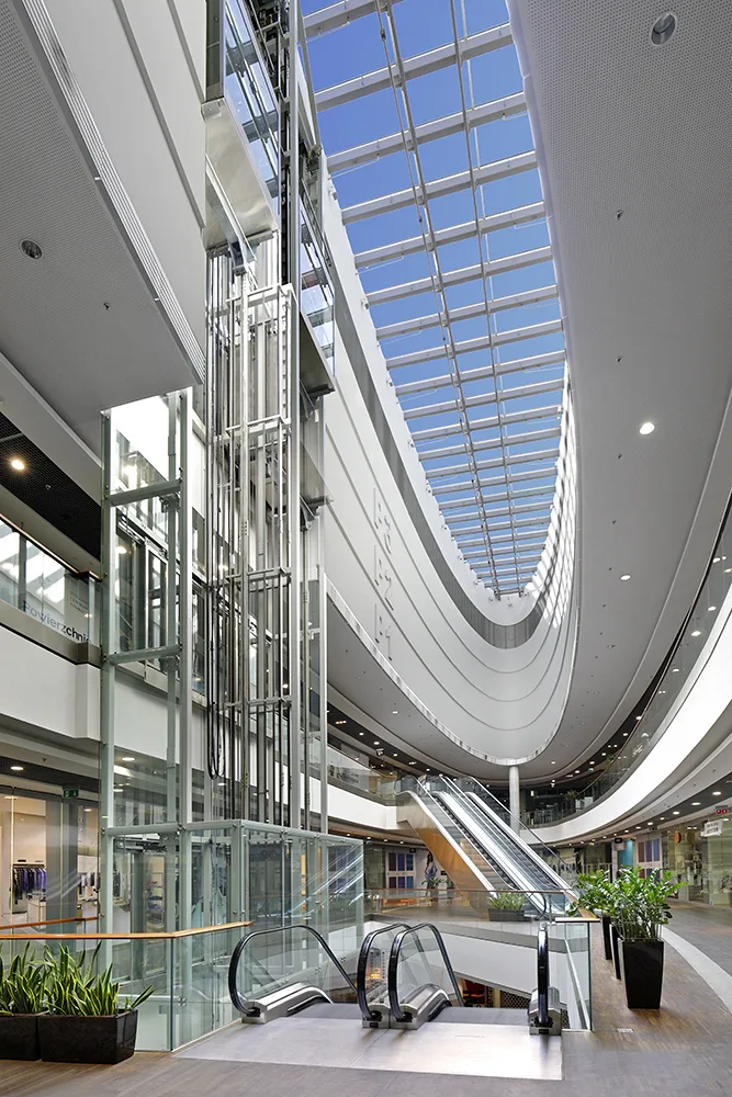 Exterior: portrait photograph of Drukarnia Mall facade detail showing vertical signage element and building entrance approach