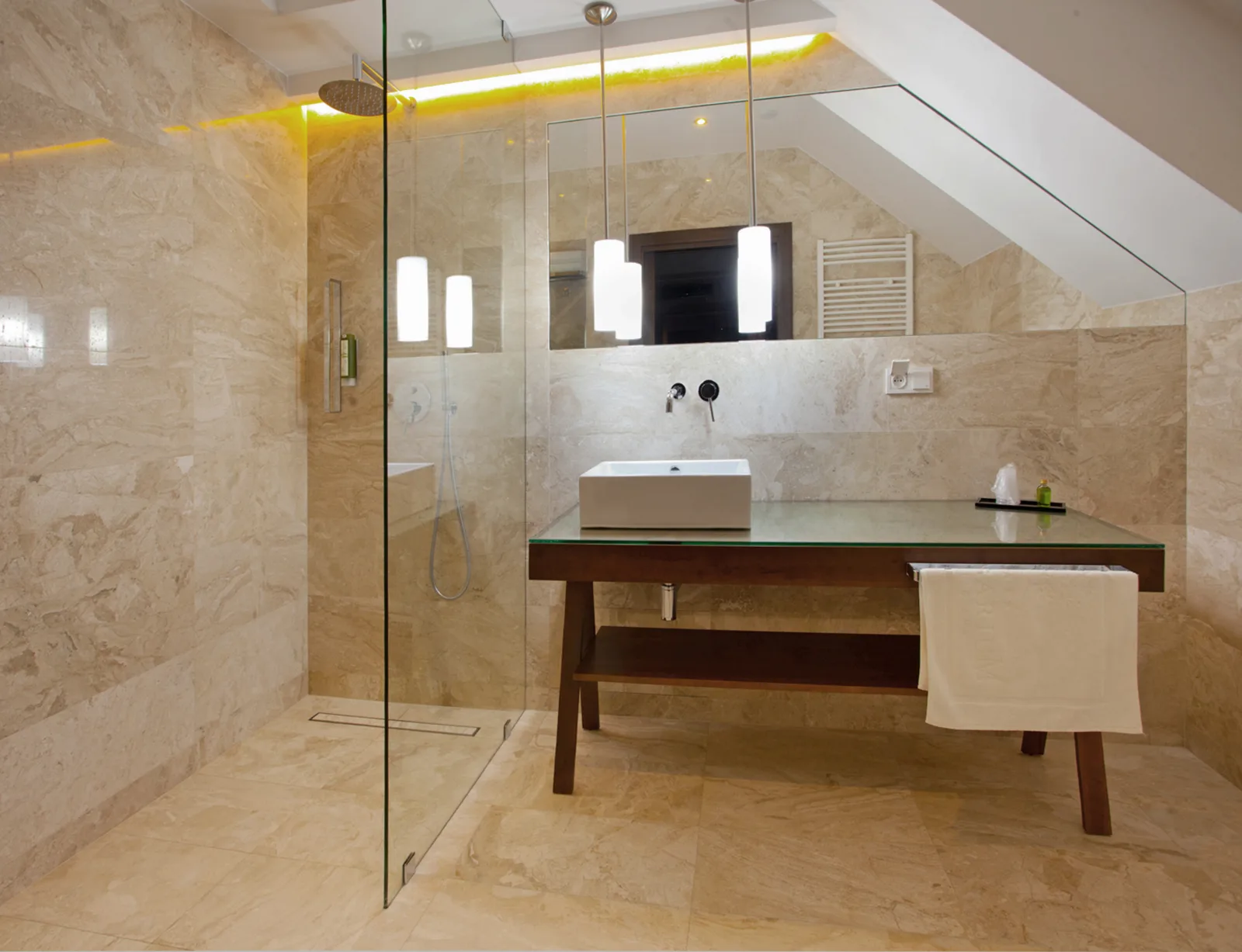 Luxury bathroom with travertine stone cladding, walnut vanity unit, and mirrored sliding doors reflecting the warm material palette