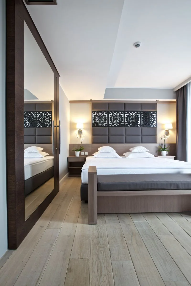 Guest room with mirror reflecting botanical headboard, bedside lamps, and warm ambient lighting