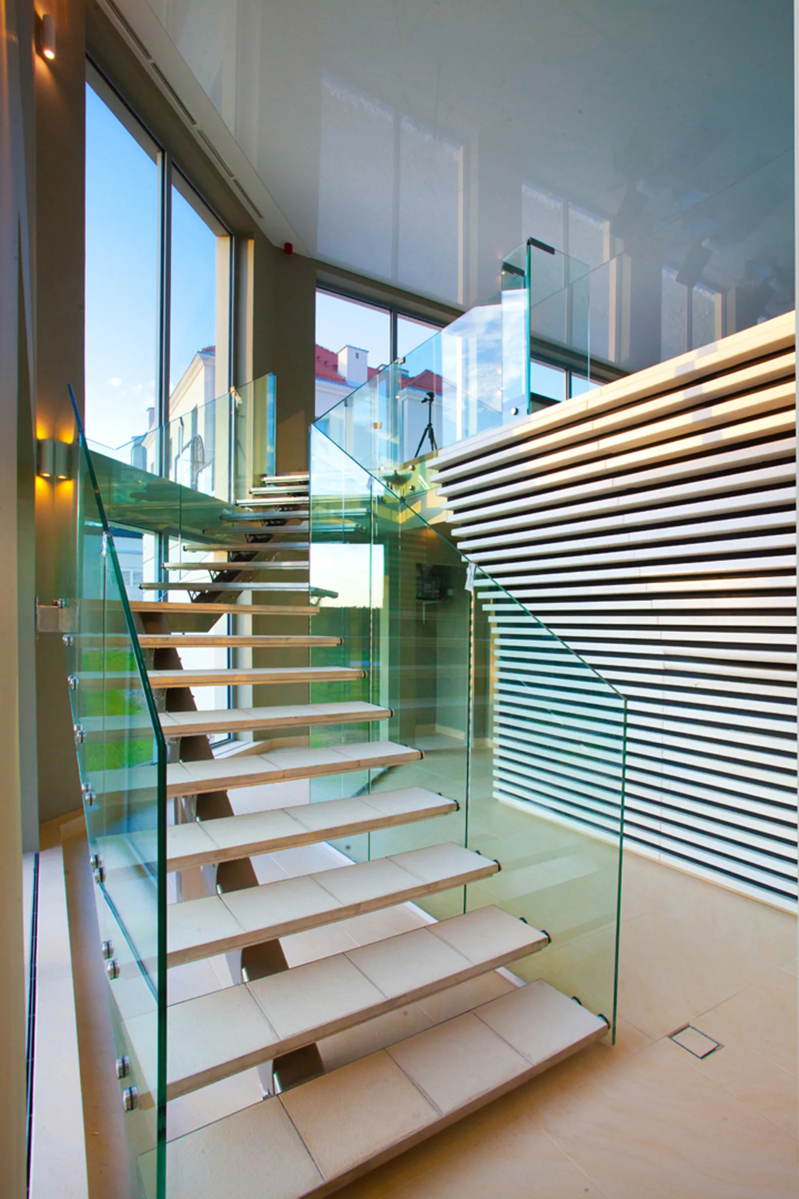 Sculptural staircase with open-tread oak steps, glass balustrade, and timber louver screen partition