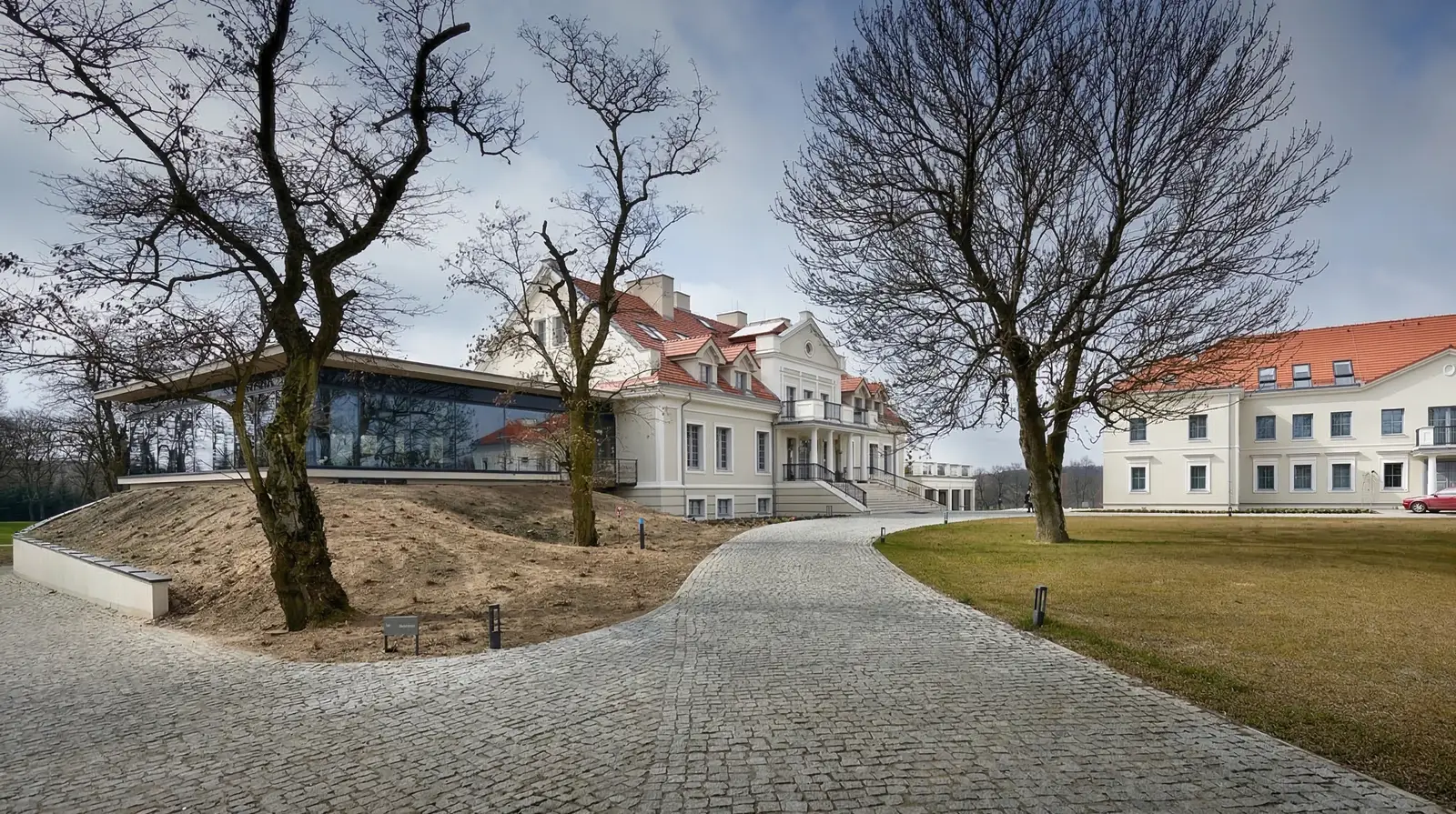 Three-building estate panorama in autumn showing Old Manor, New Manor, and Annexe set within the 19th-century landscaped park beside Lake Chomiaskie