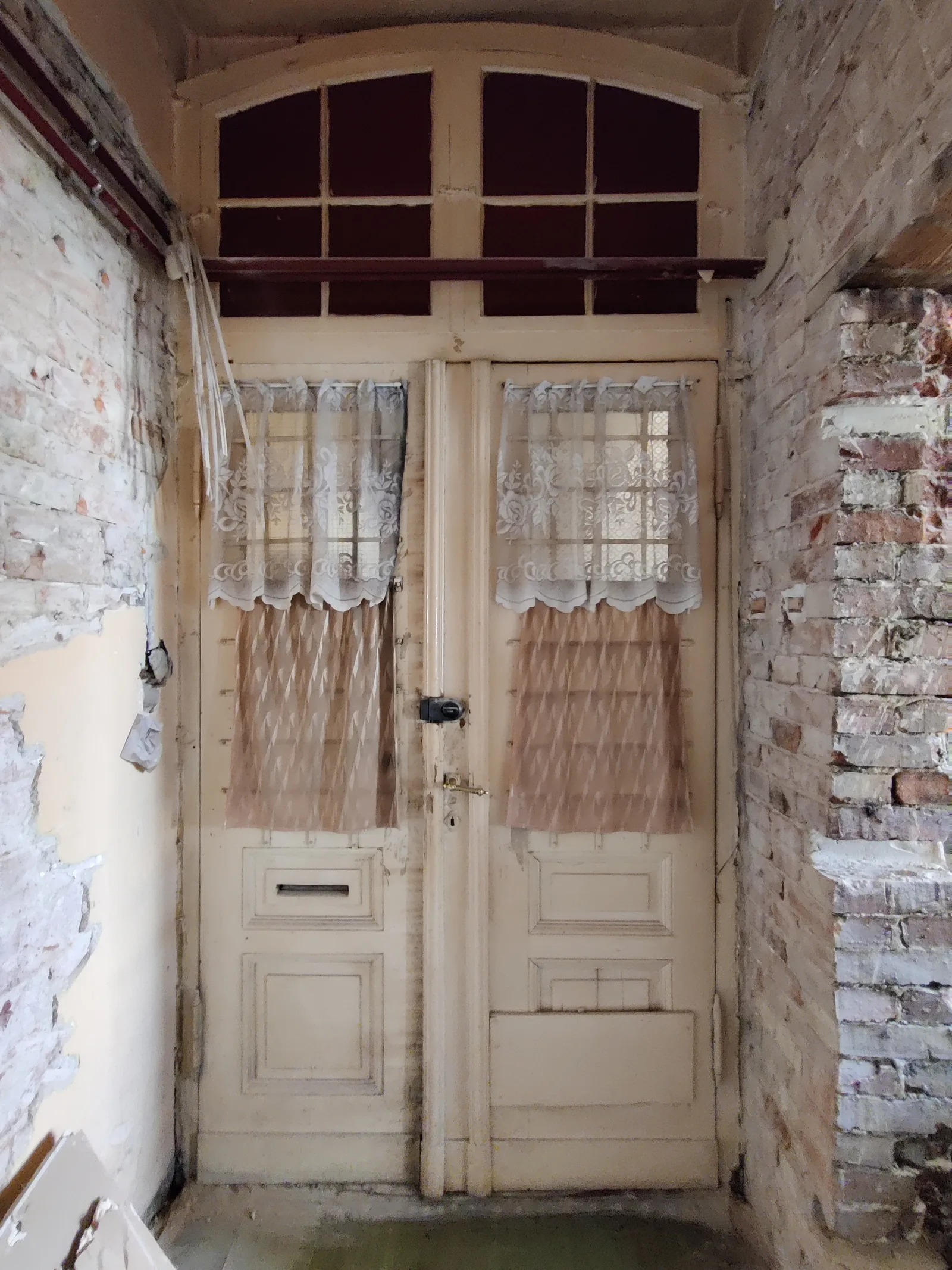 Before: pre-renovation room interior showing high tenement ceiling, original timber window with deep reveal, and bare plaster walls awaiting conversion