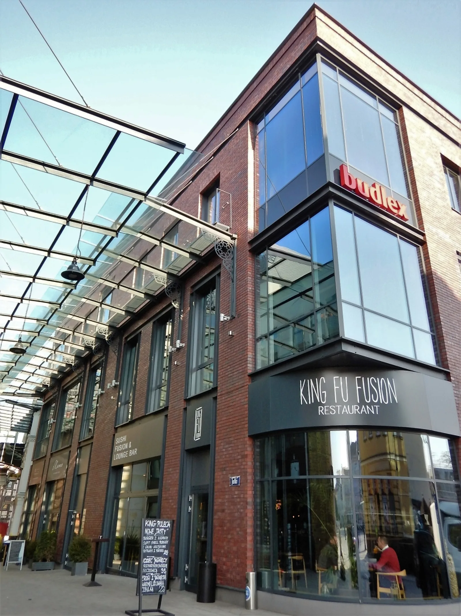 Exterior: Jatki complex two-storey building elevation with glass canopy, red brick, and King Fu Fusion signage at corner
