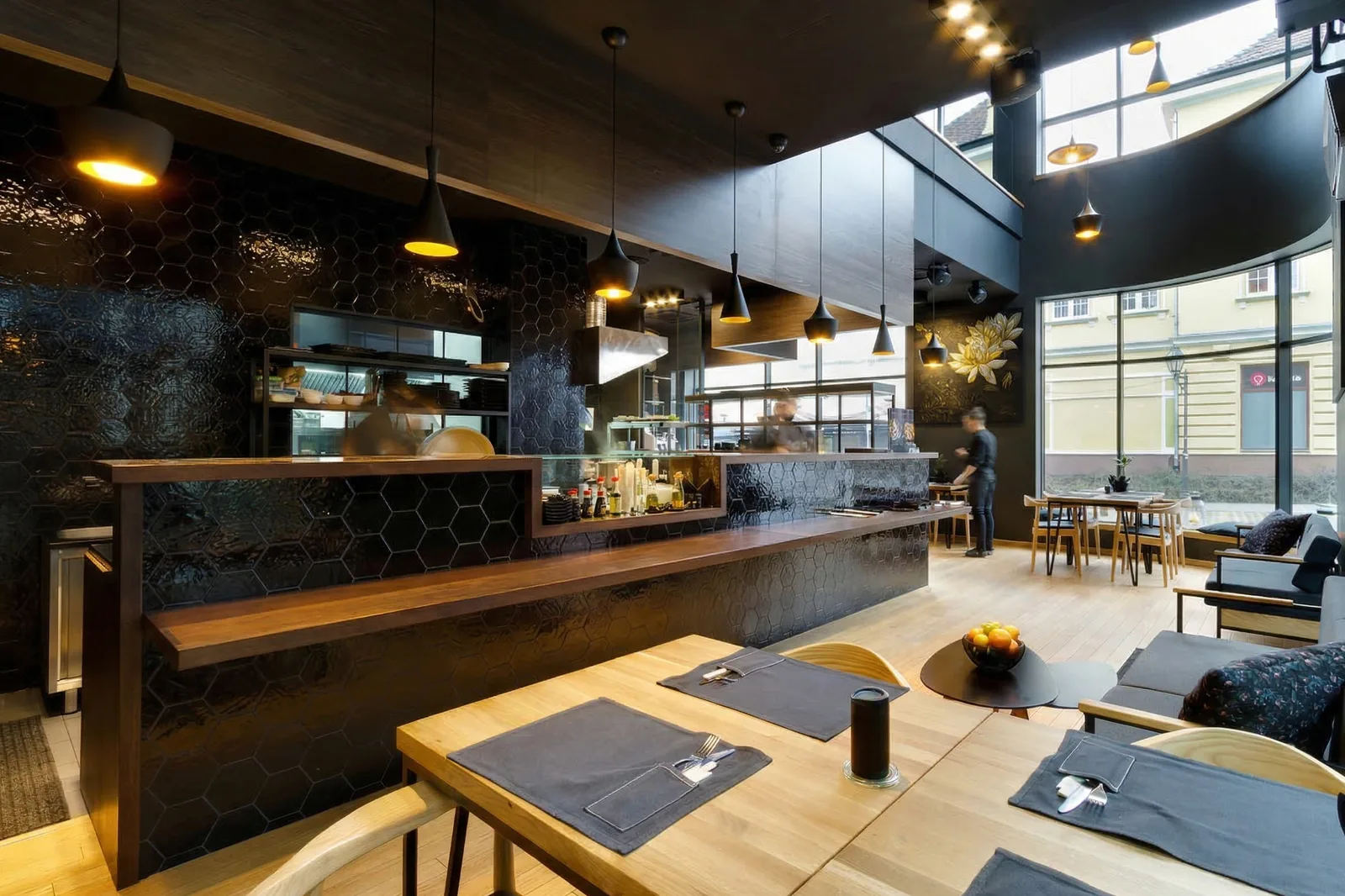 Interior: ground floor dining area with sushi bar counter, hexagonal tile backsplash, oak tables, and full-height glazing to street