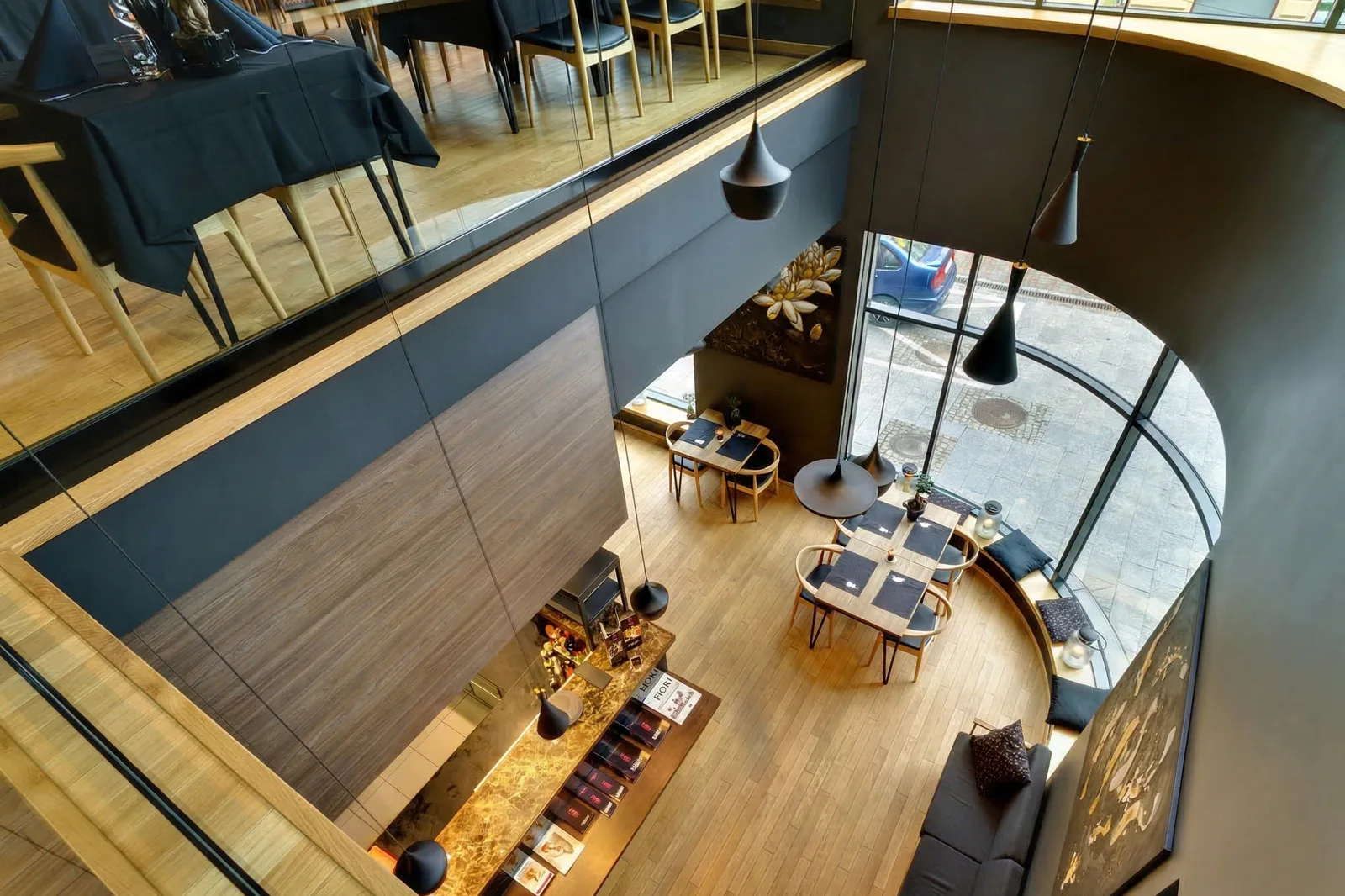 Interior: bird's-eye view from upper floor looking down to ground floor through curved glazing, double-height void, sushi bar, and Tom Dixon pendants