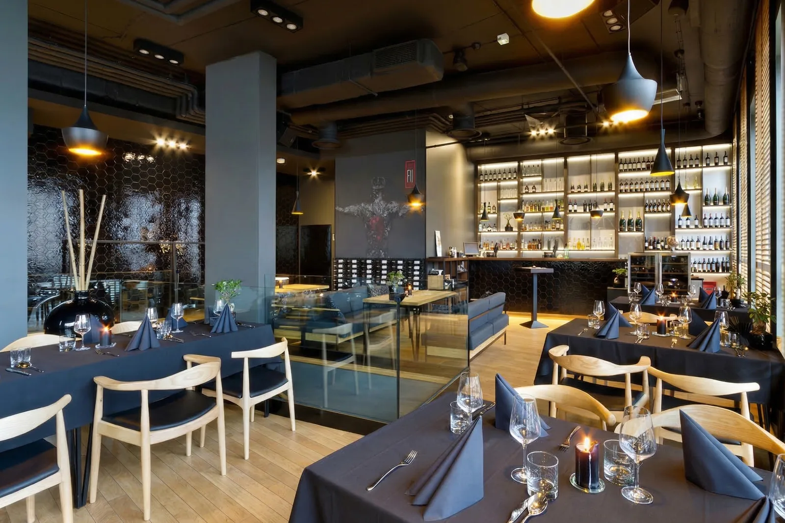 Interior: upper floor dining room with dark tablecloths, wine display wall, warrior mural, exposed ductwork, and candle-lit tables