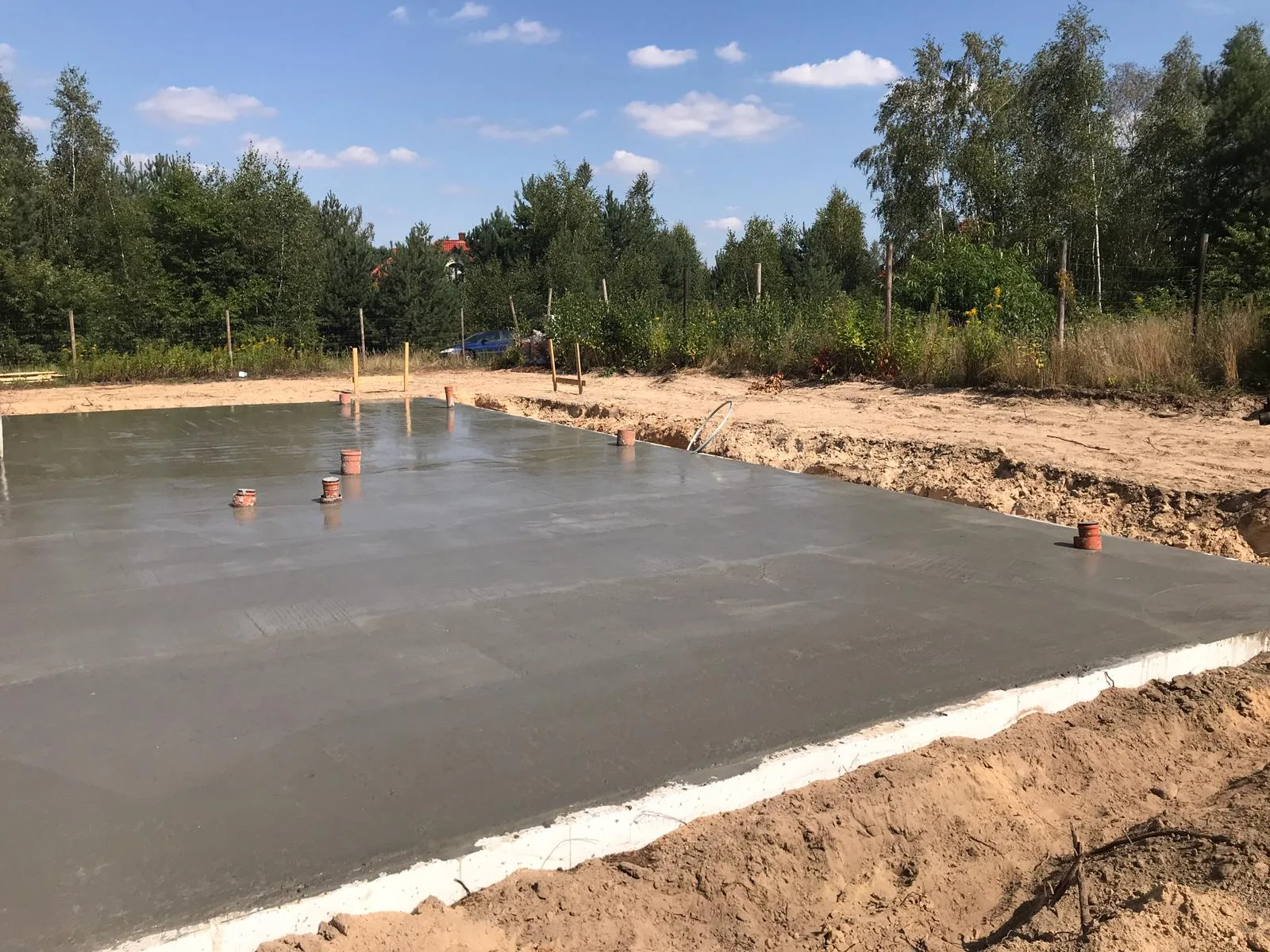 Construction: foundation progress photograph showing the concrete slab with white EPS perimeter insulation boards and reinforcement mesh visible during the August 2019 build phase
