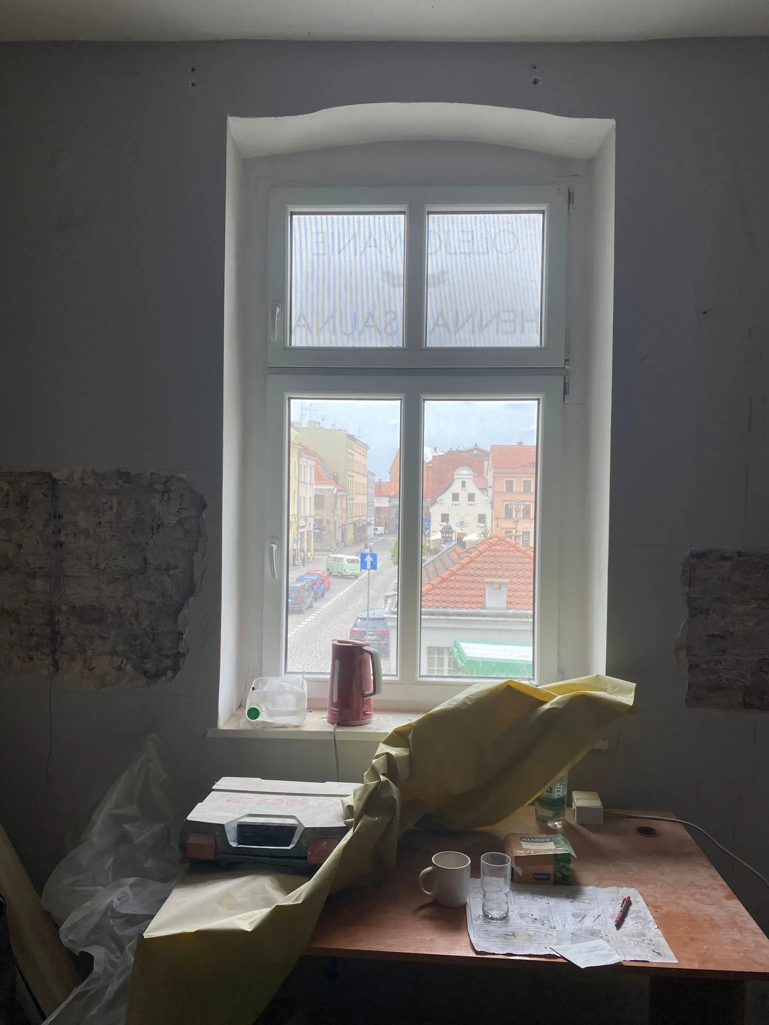 Construction: building materials staged on site including drywall sheets and timber battens with partially completed partitions visible beyond