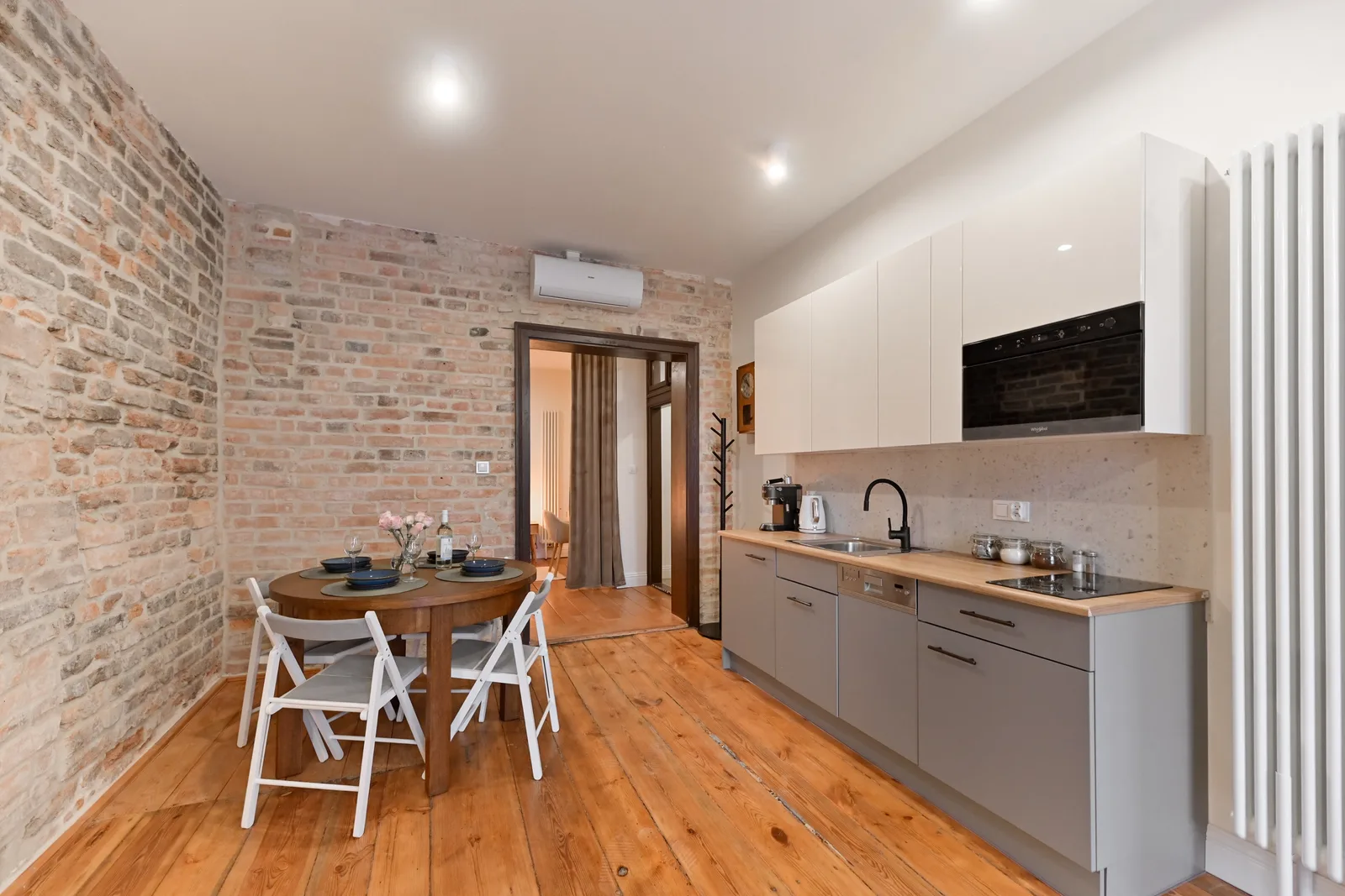 Interior: Apartment B bedroom with curtain room divider, exposed brick, timber ceiling beams, pendant light, and warm natural wood tones