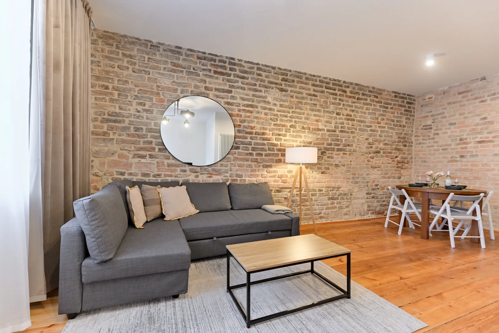 Interior: Apartment B panoramic showing kitchen-dining open-plan layout with exposed brick walls, timber ceiling structure, and modern furniture