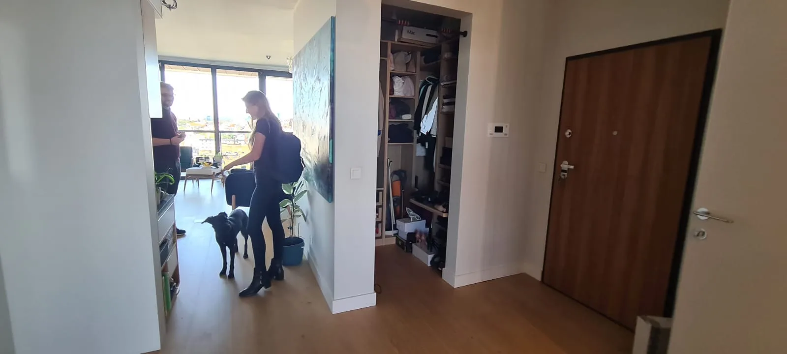 Documentary: pre-renovation master bedroom photograph showing petrol blue teal accent wall, wooden bed frame, and panoramic Bydgoszcz city views through floor-to-ceiling windows — the apartment's strongest asset
