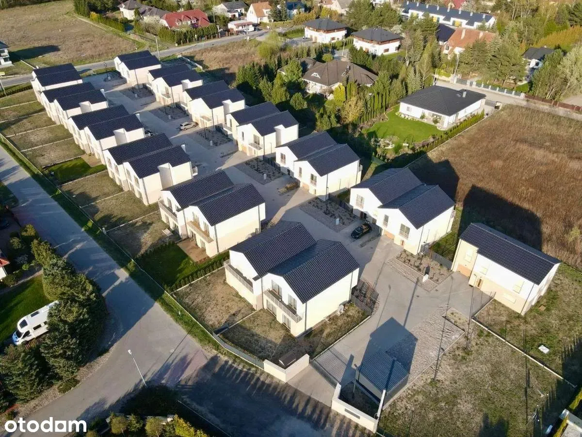 High altitude drone photo showing complete 13-building estate from above with all semi-detached houses, Type C detached unit at corner, and suburban landscape context