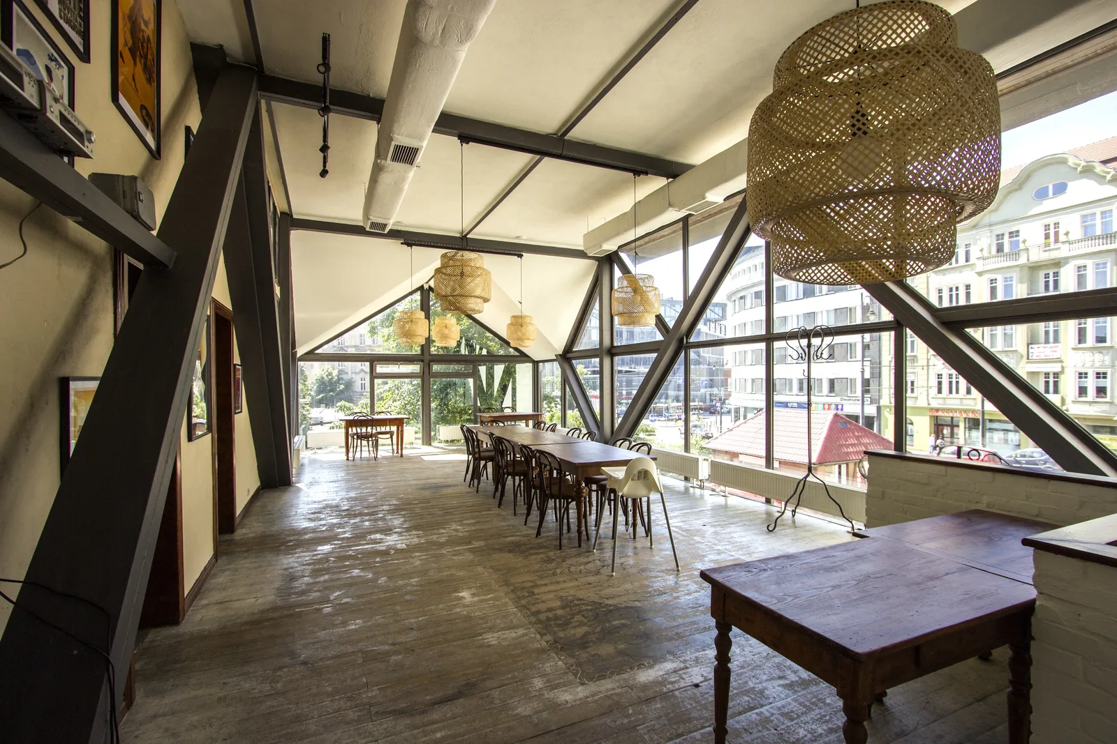 Ground floor full-length view showing Chesterfield banquette, bentwood chairs, poster gallery, and garden terrace connection through the windows