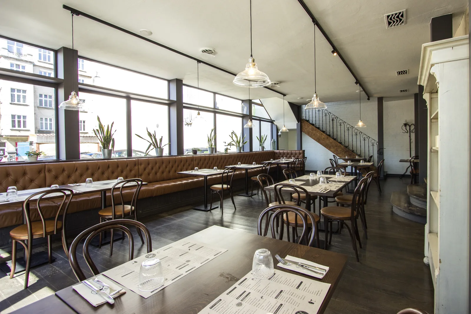 First floor dining hall showing the full length of the communal table under rattan pendants with triangular windows along the wall