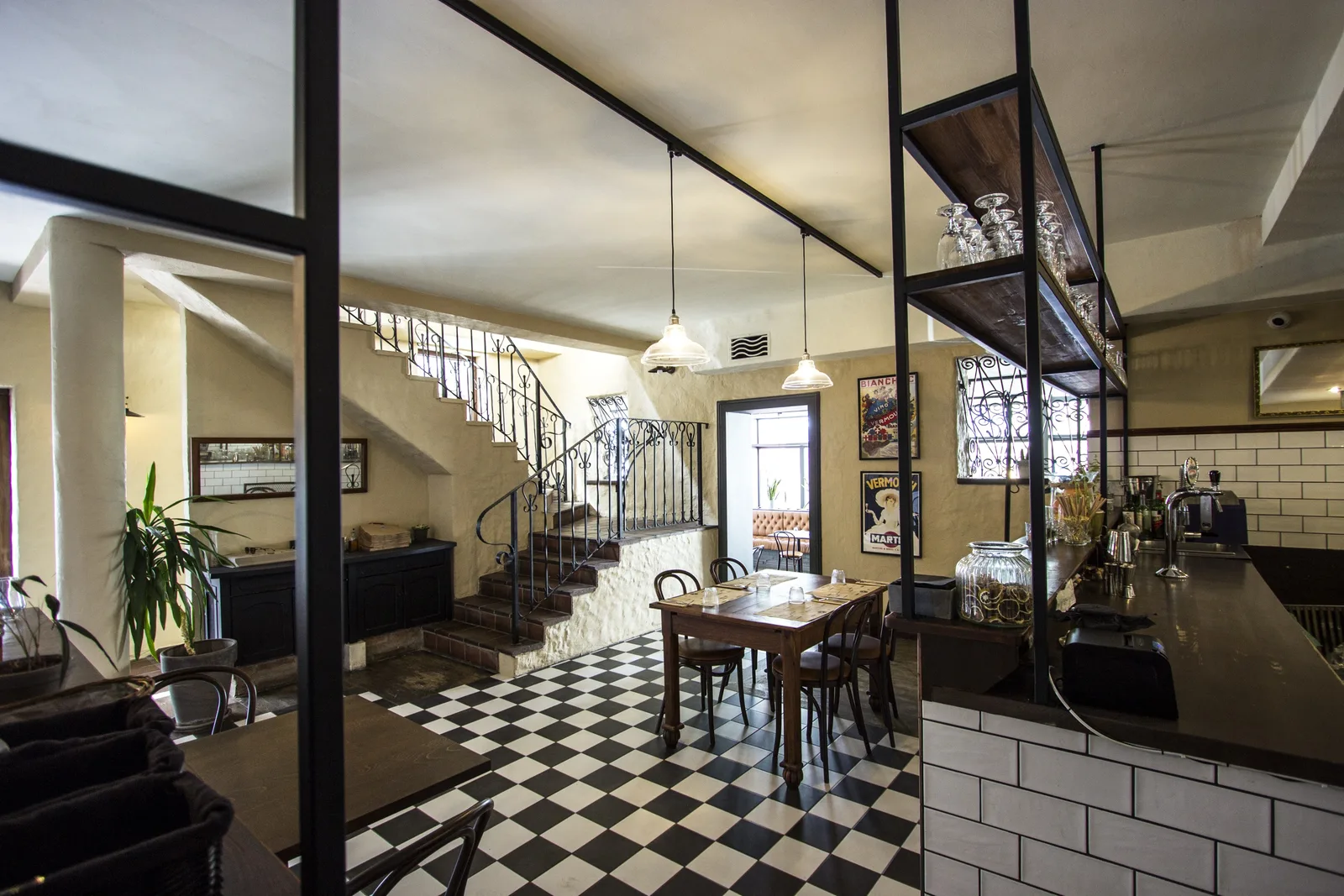 Ground floor dining vignette with vintage poster trio, warm pendant light, bentwood chairs, and dark stained timber floor