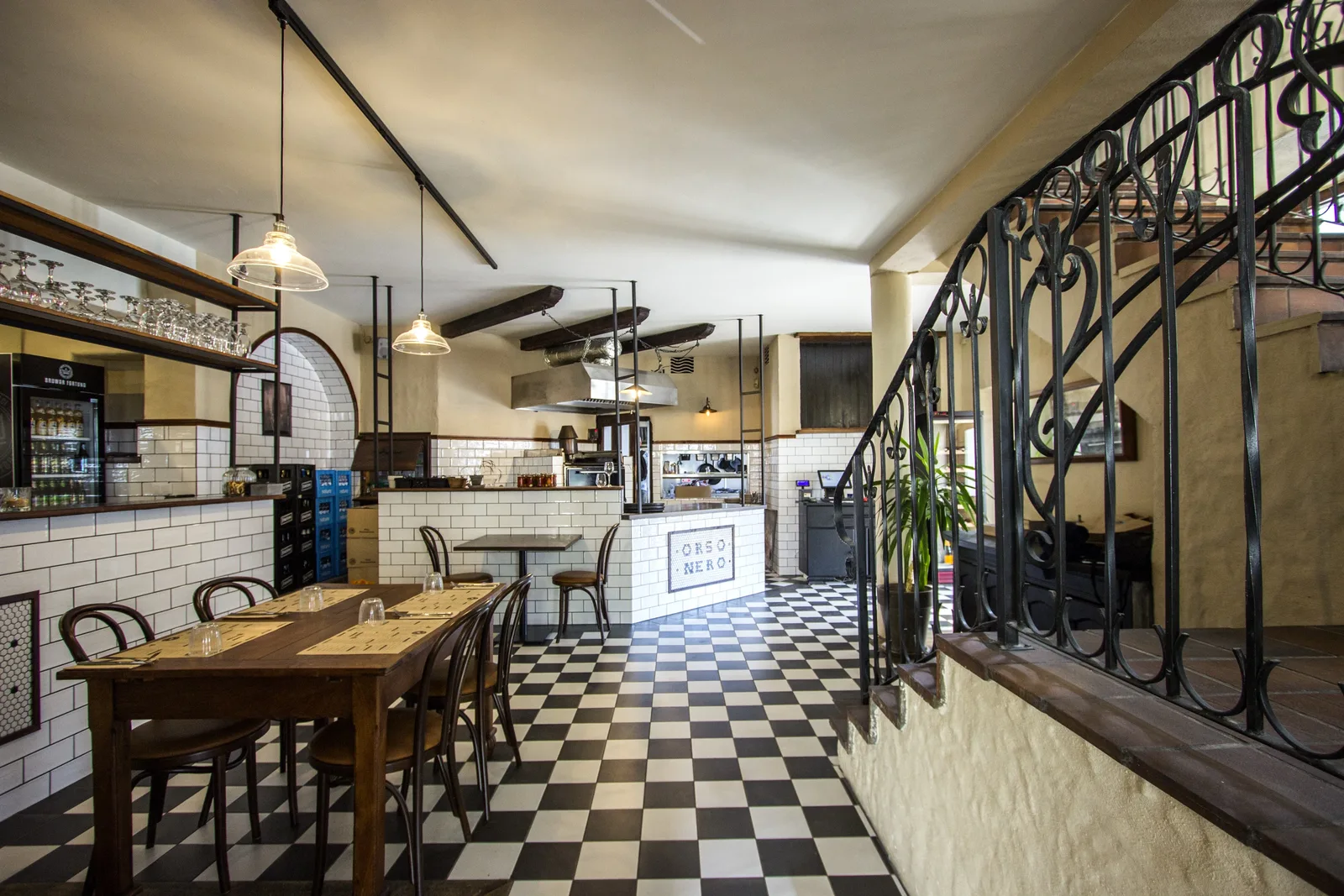 First floor dining from the stairwell entrance showing the dramatic height, exposed timber roof structure, and rattan pendant constellation