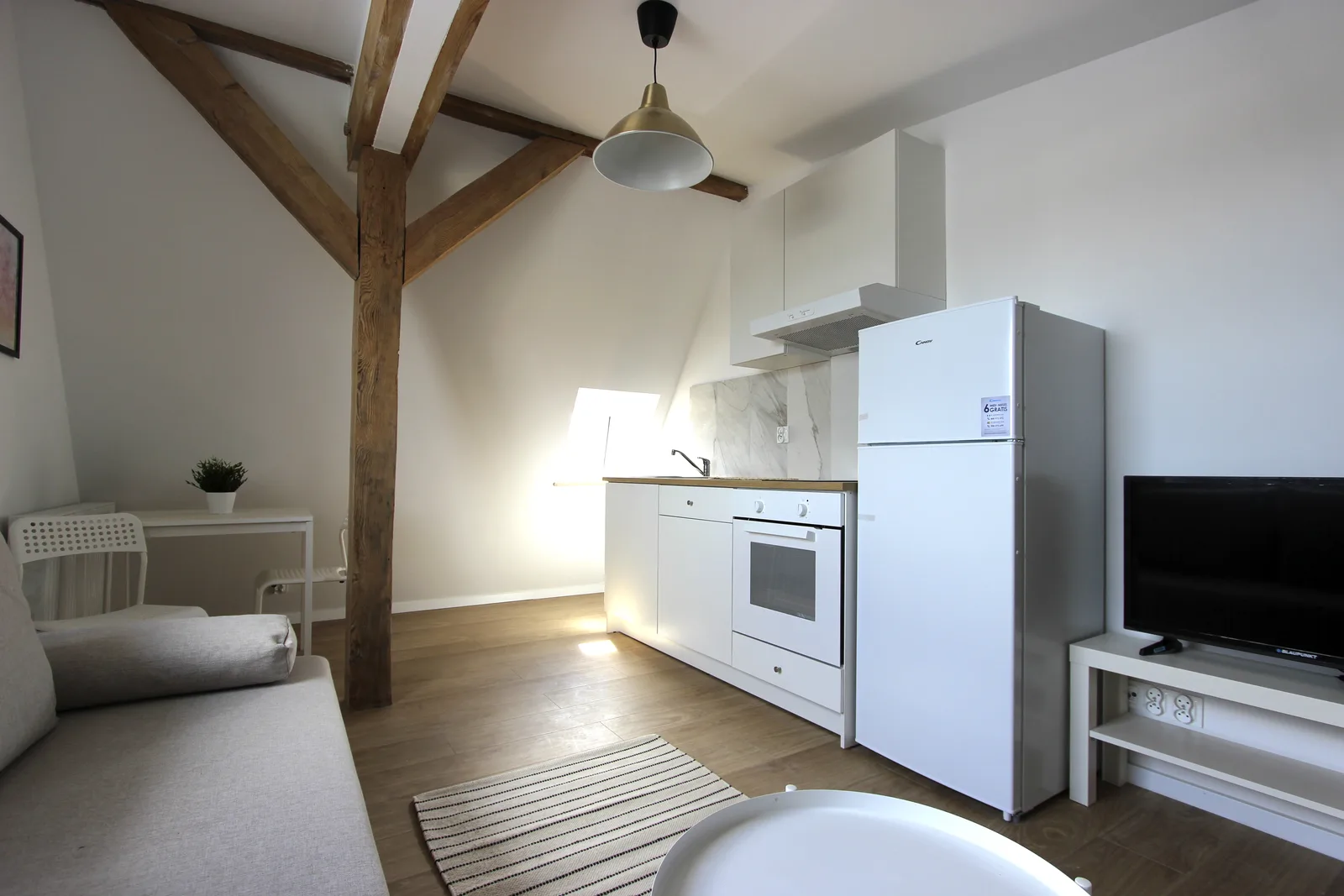 Interior: kitchen with marble-effect splashback accent, V-shaped timber cross-brace beam overhead, Ablux light oak laminate flooring, and efficient compact layout for rental apartment living