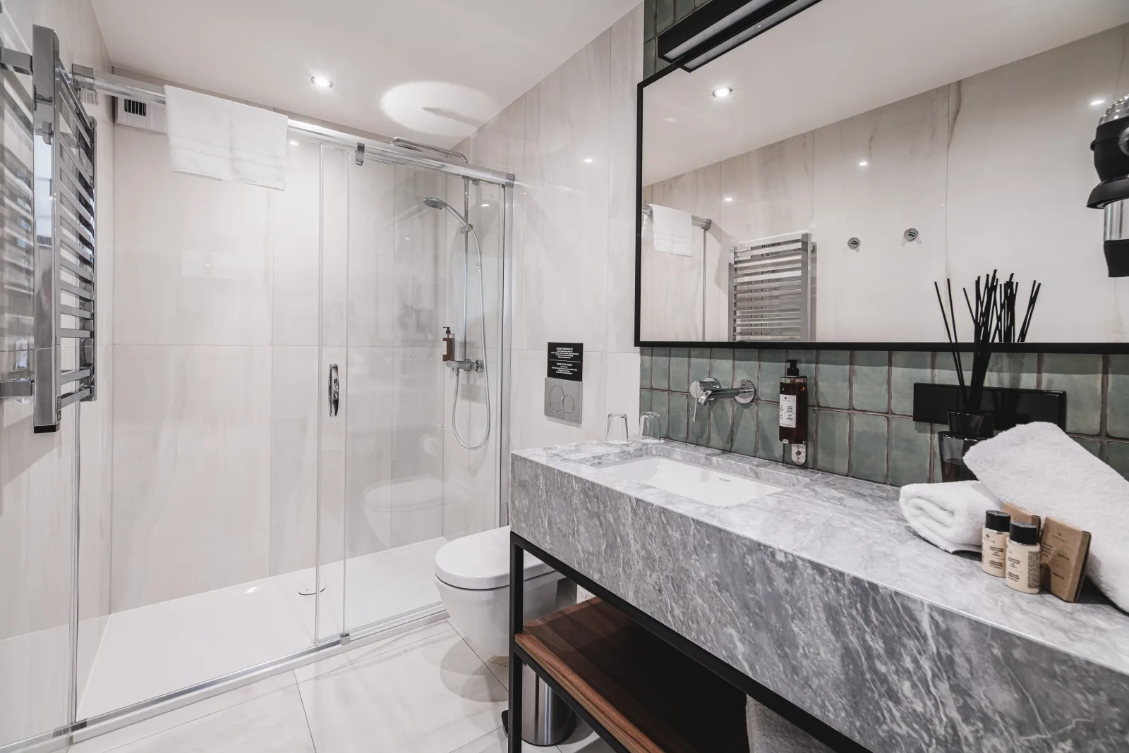 Marble vanity with towels, glass shower partition