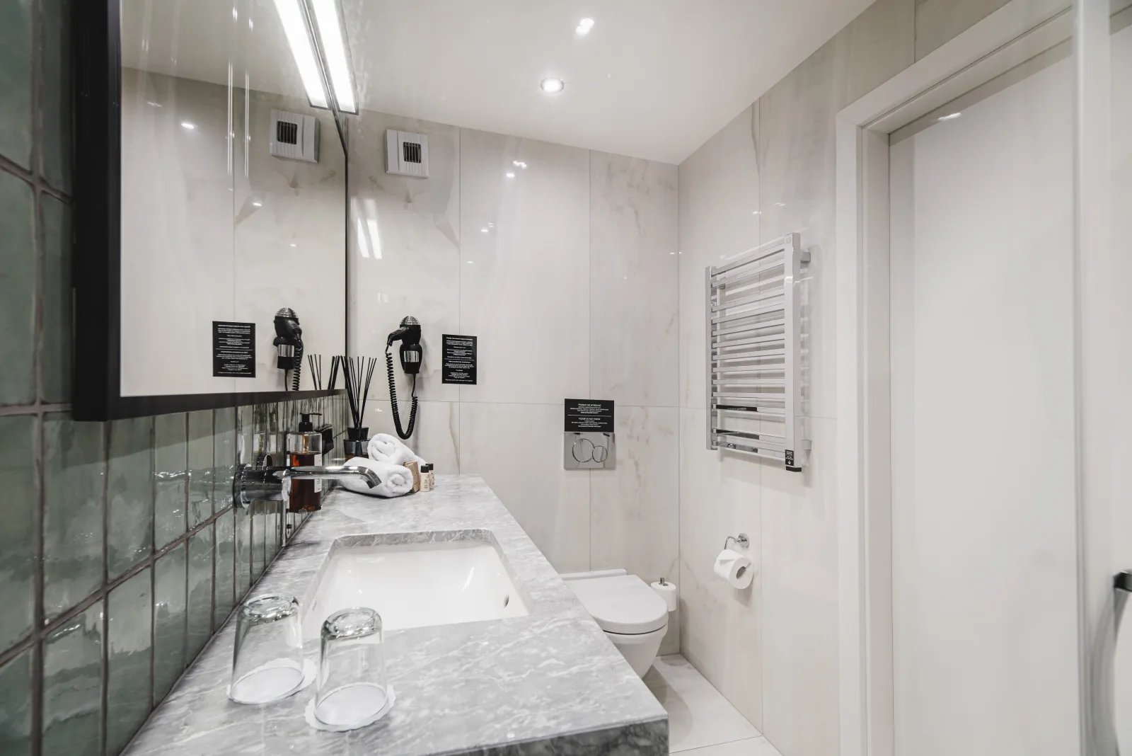Bathtub with green zellige tile surround, marble ledge