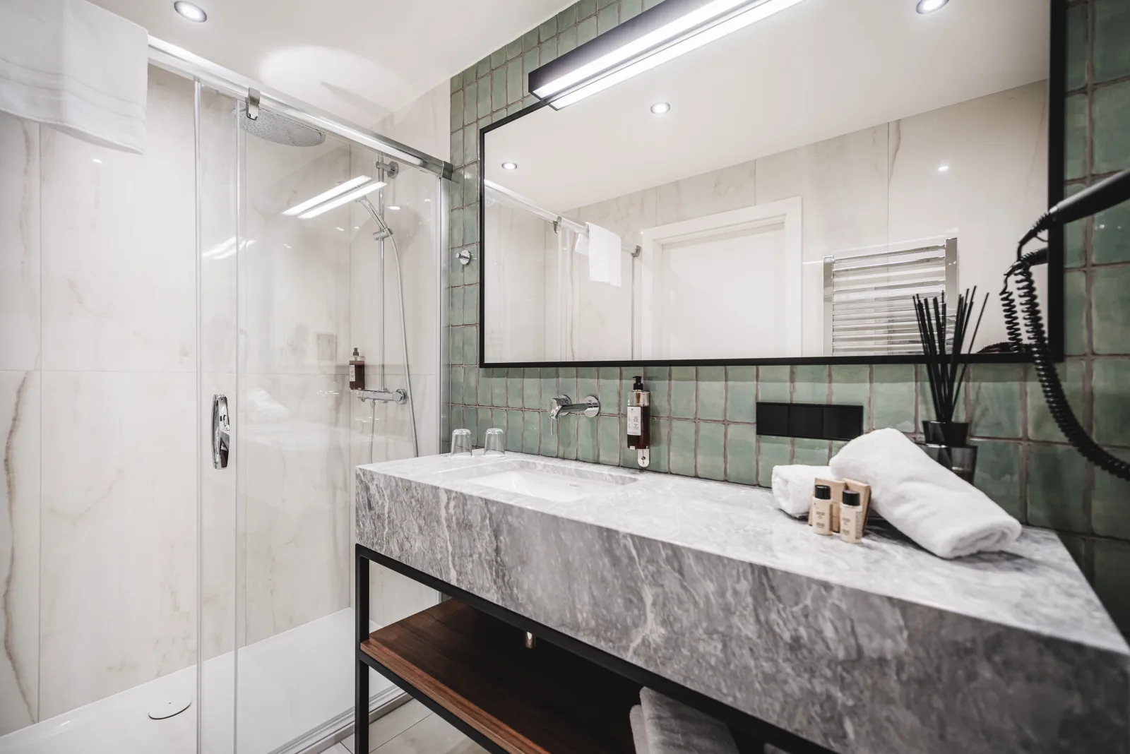 Marble vanity close-up with towels, shower visible behind