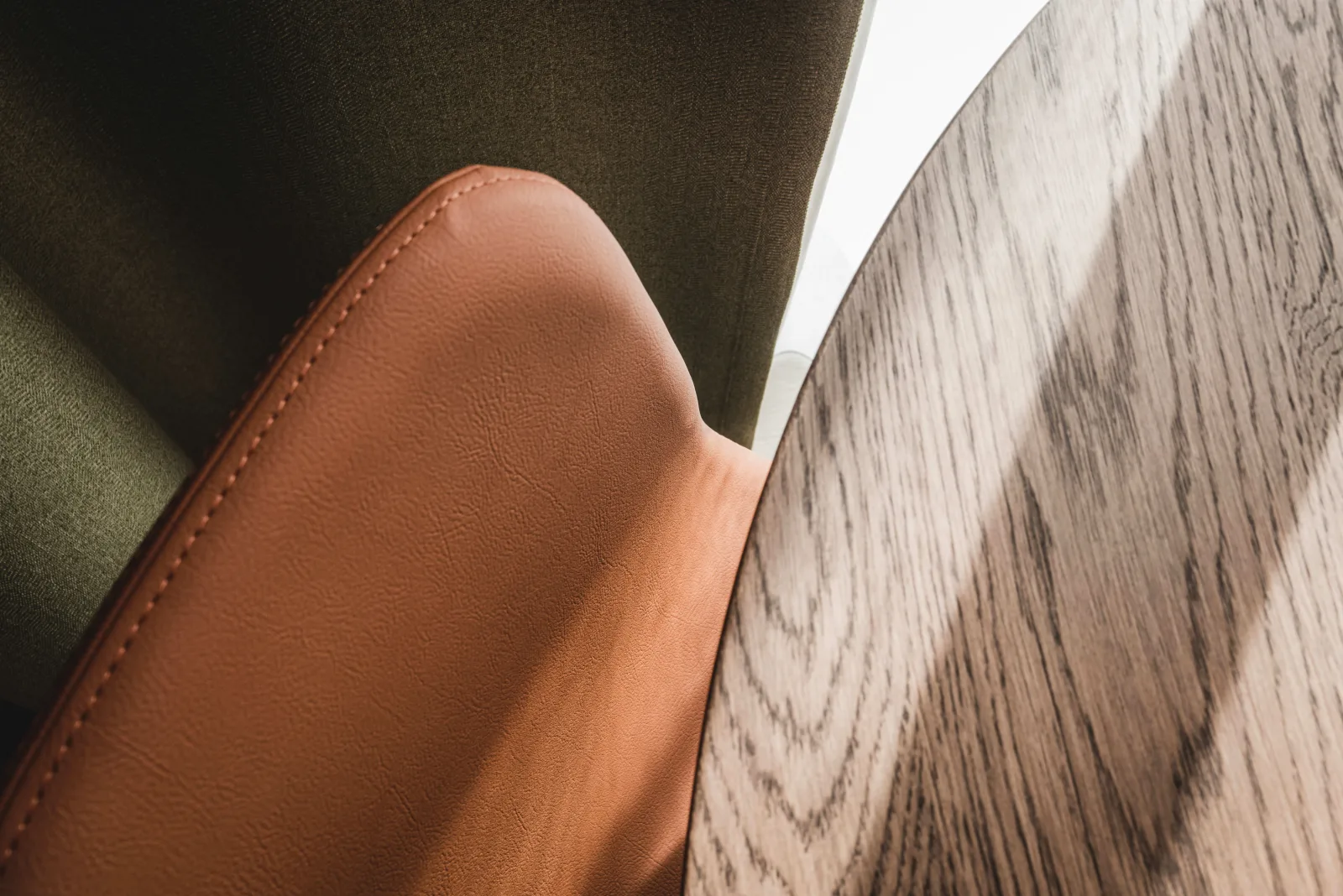 Brown leather chair armrest close-up with warm sunlight