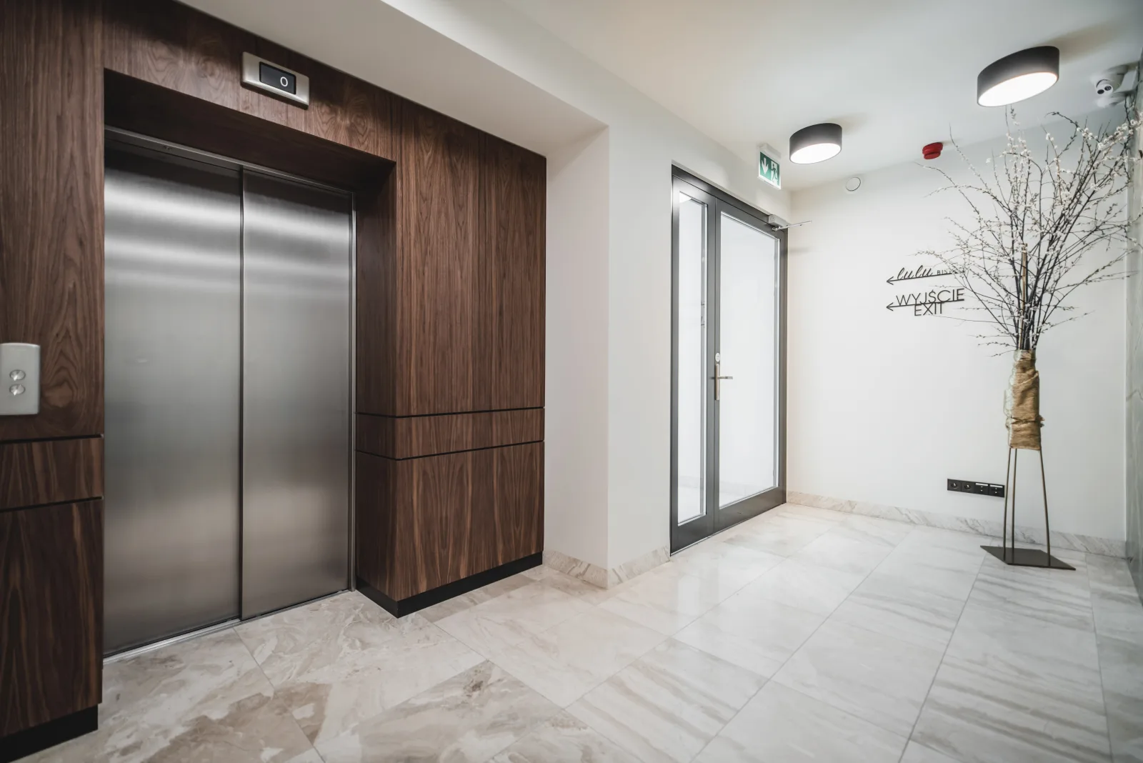 Elevator lobby with wooden apartment doors and marble floor
