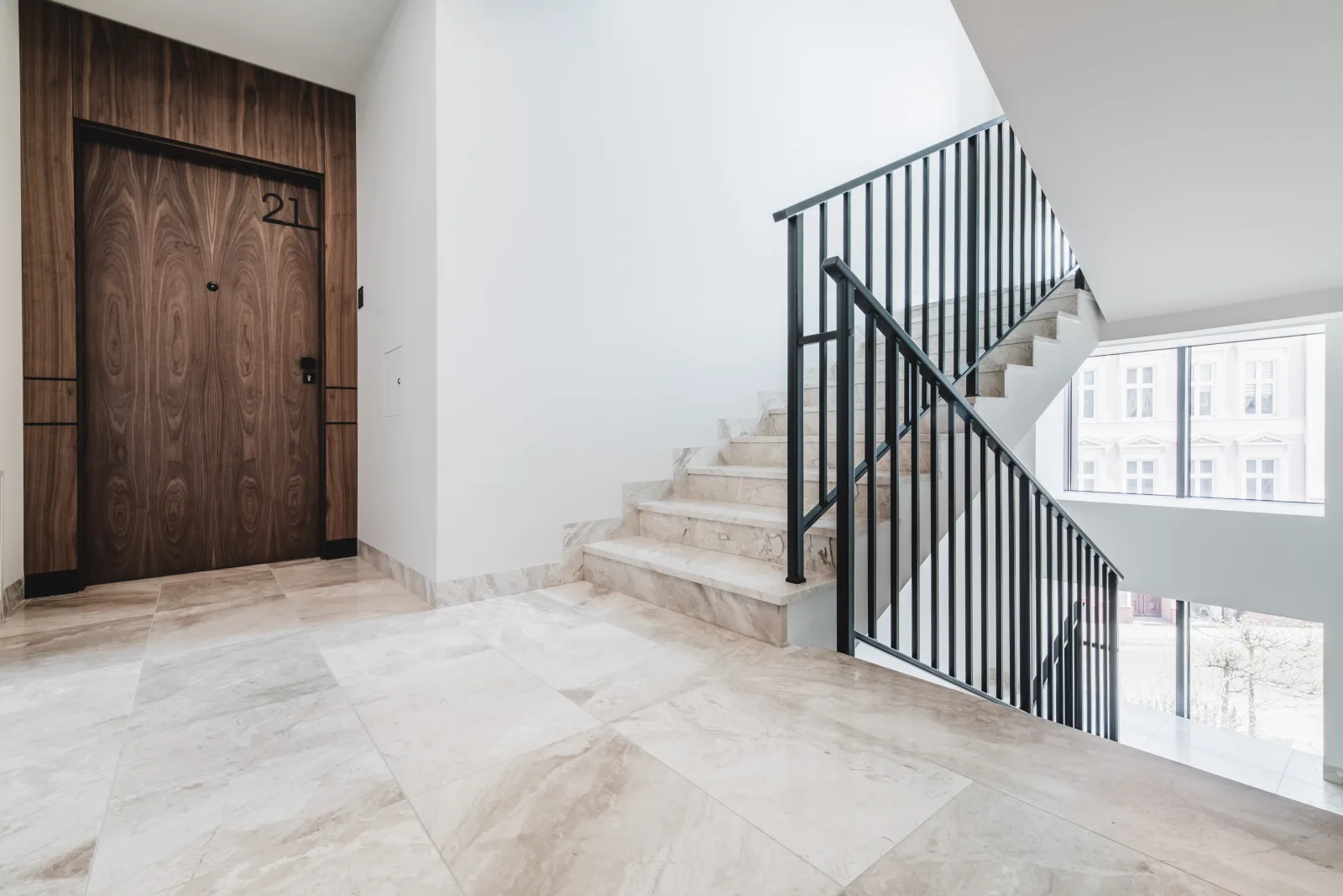 Marble staircase with black metal railing, natural light from window