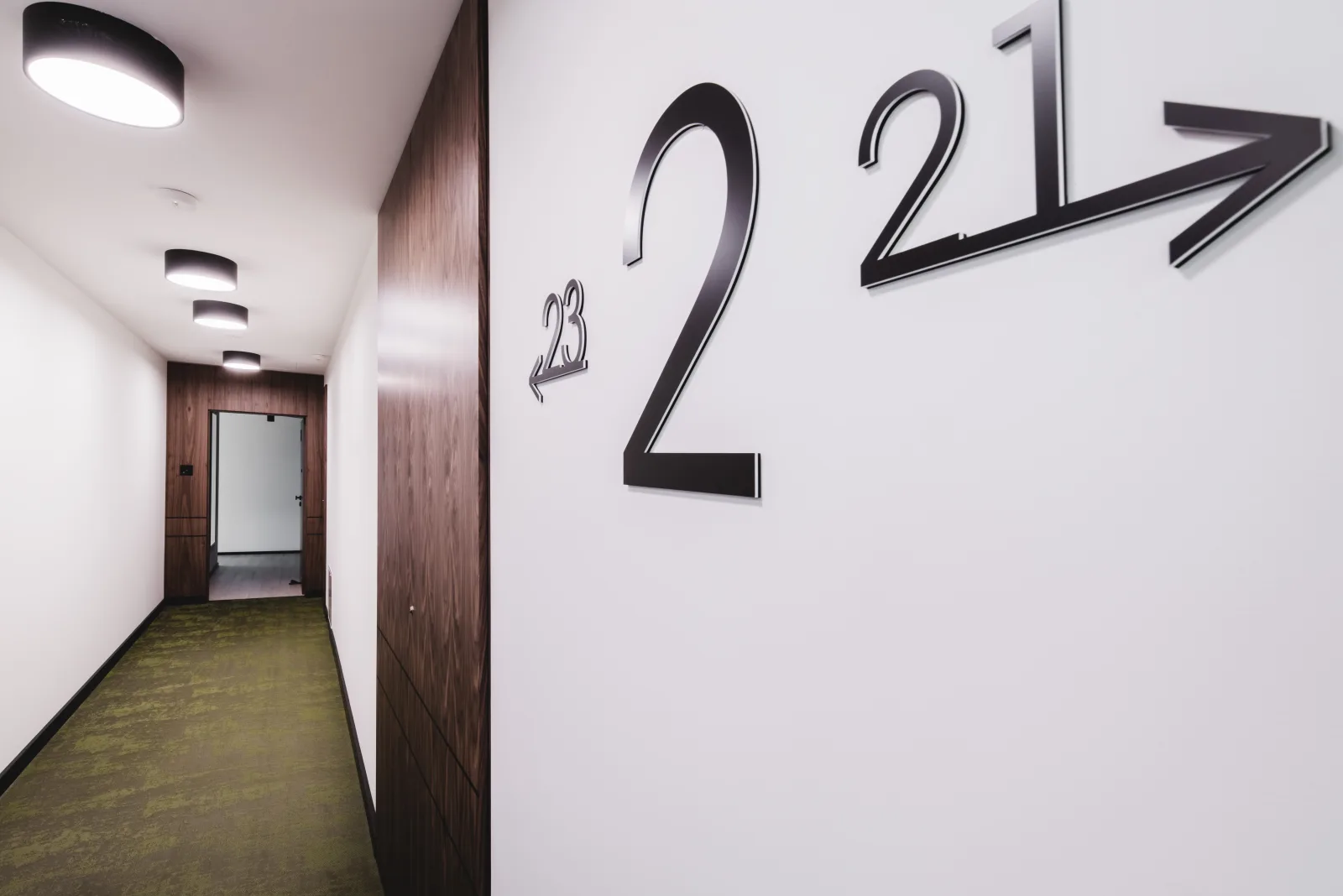 Floor number signage with directional arrow, brushed steel wayfinding