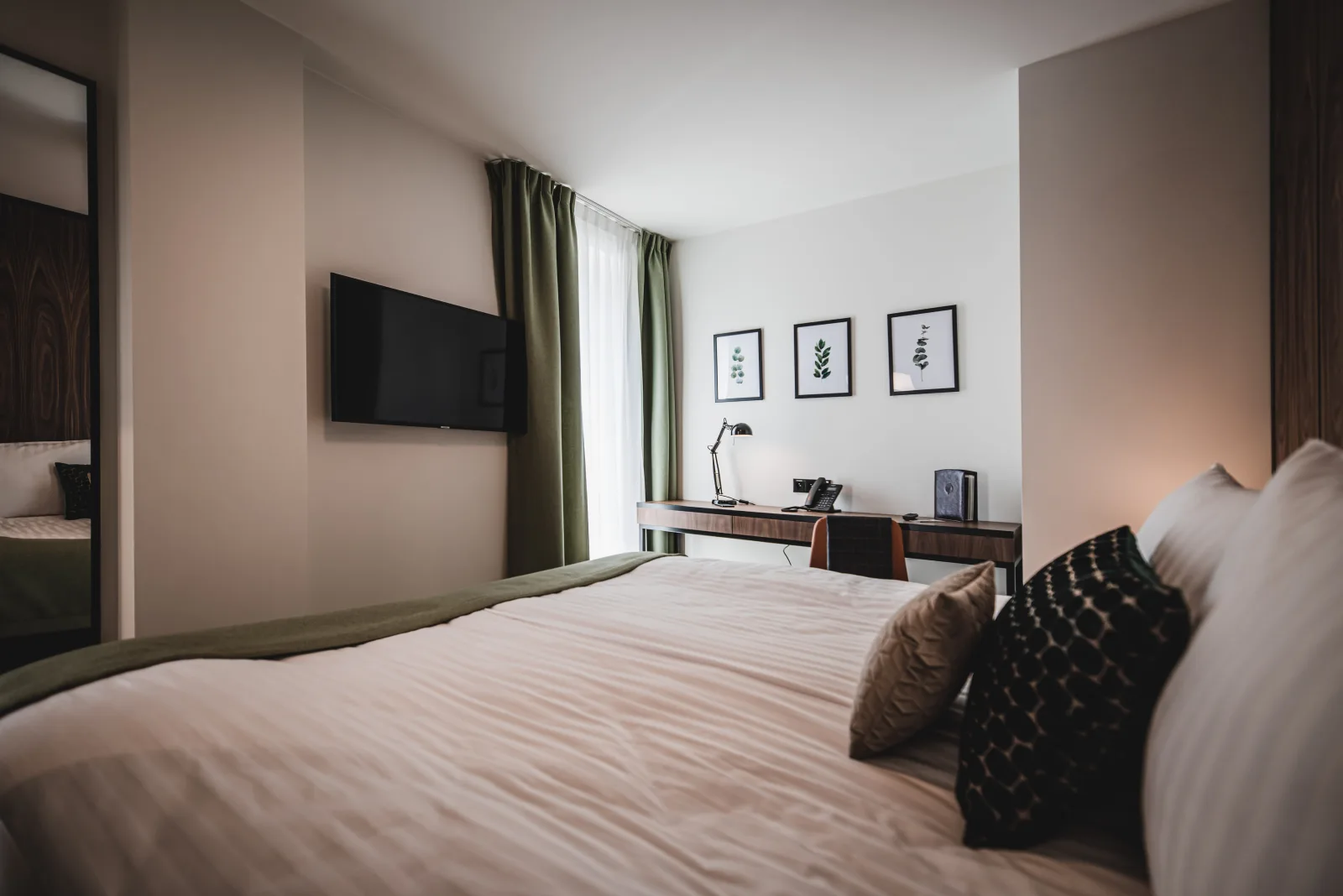 Bedroom with walnut headboard wall, TV, dark accent pillows
