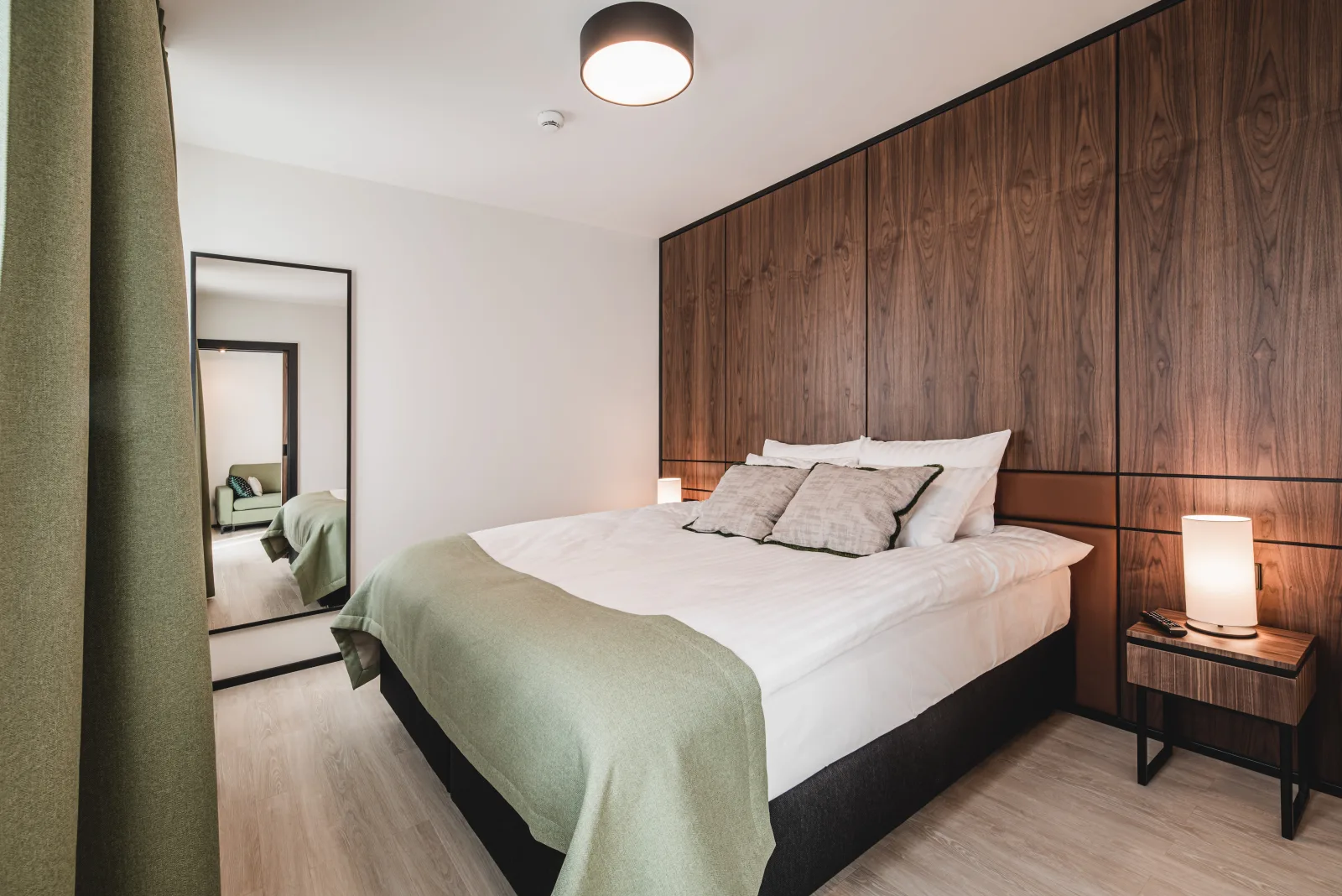 Bedroom with green curtains, white bedding, warm light