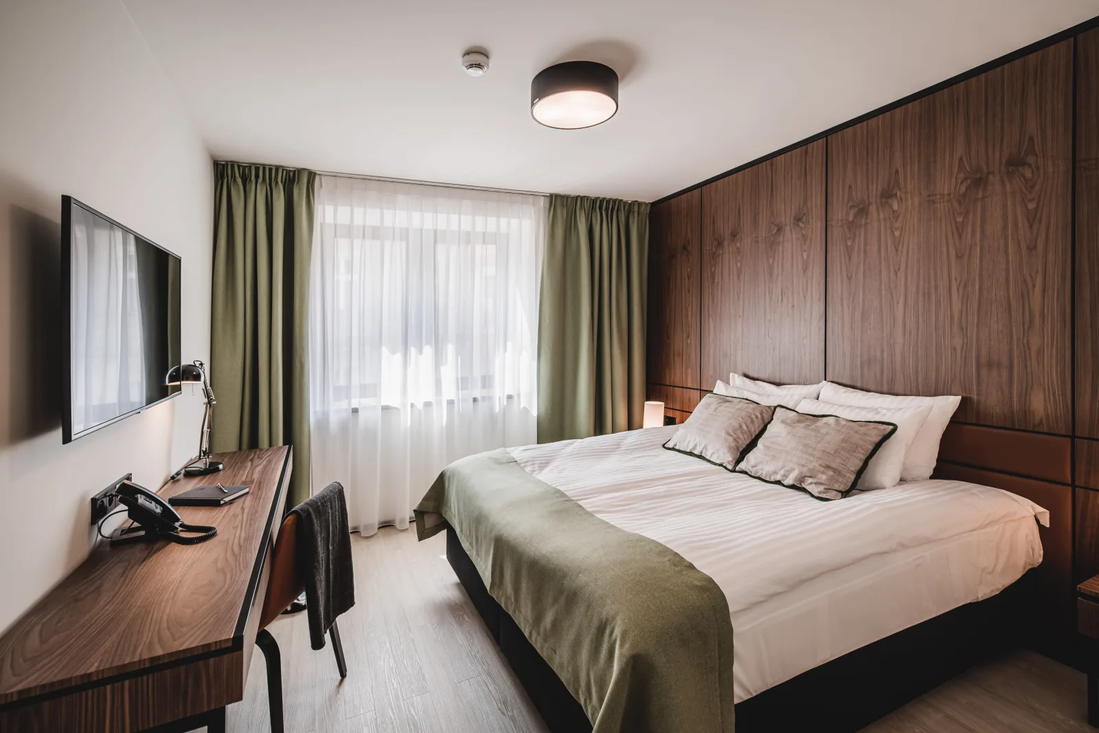 Bedroom with walnut headboard, green curtains, double bed