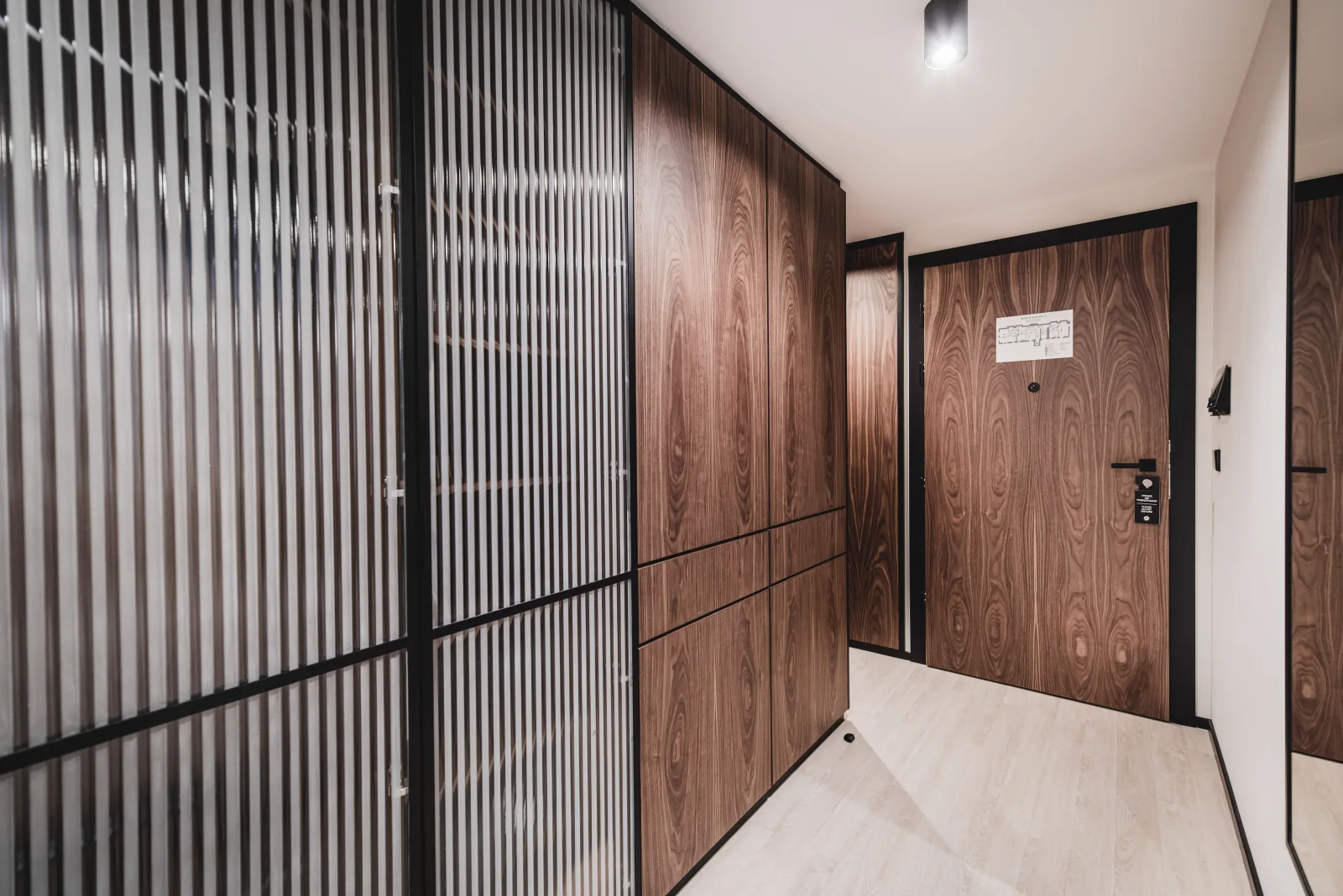 Room with fluted glass partition, hallway with walnut paneling