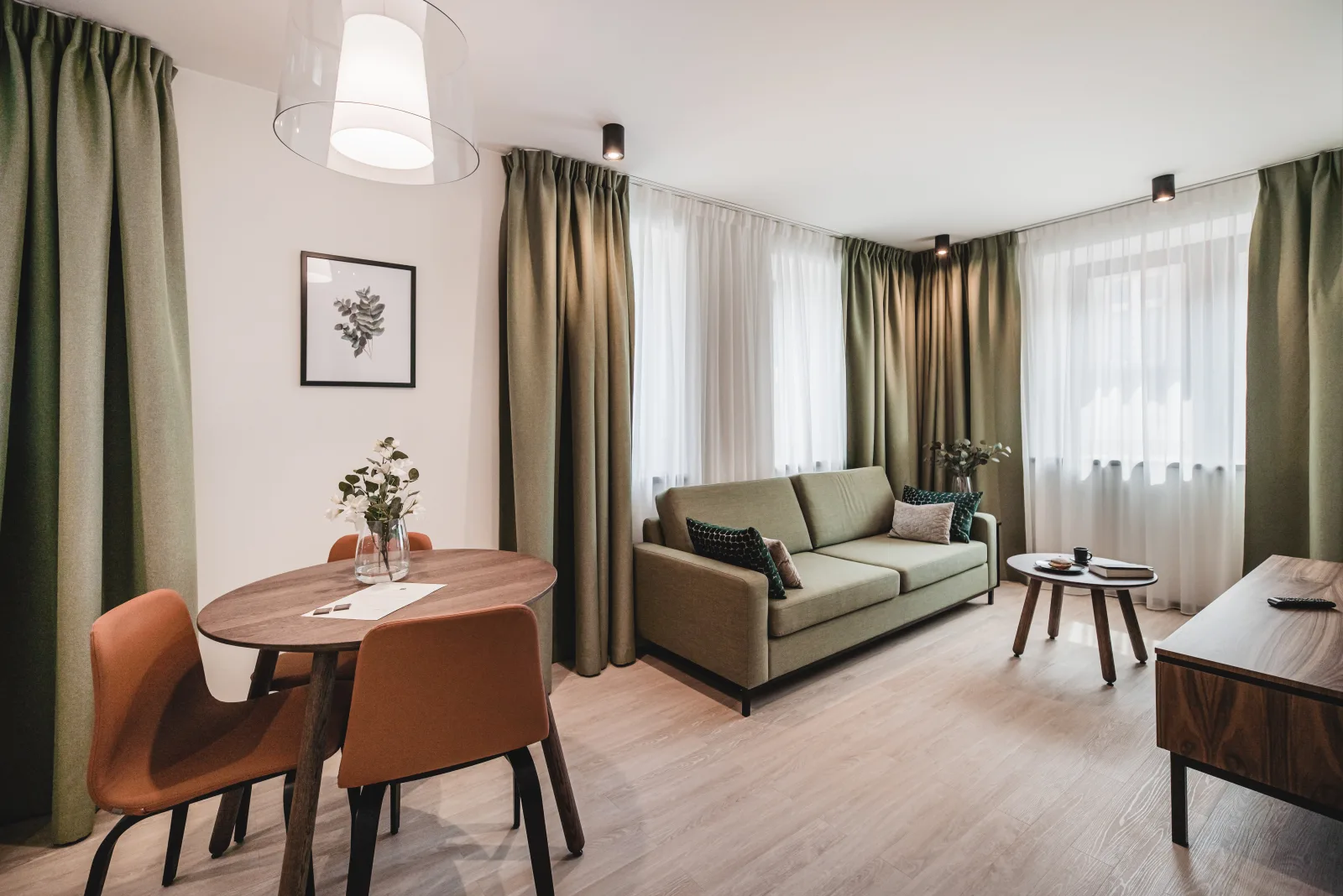 Living area with green sofa, pendant light, curtains
