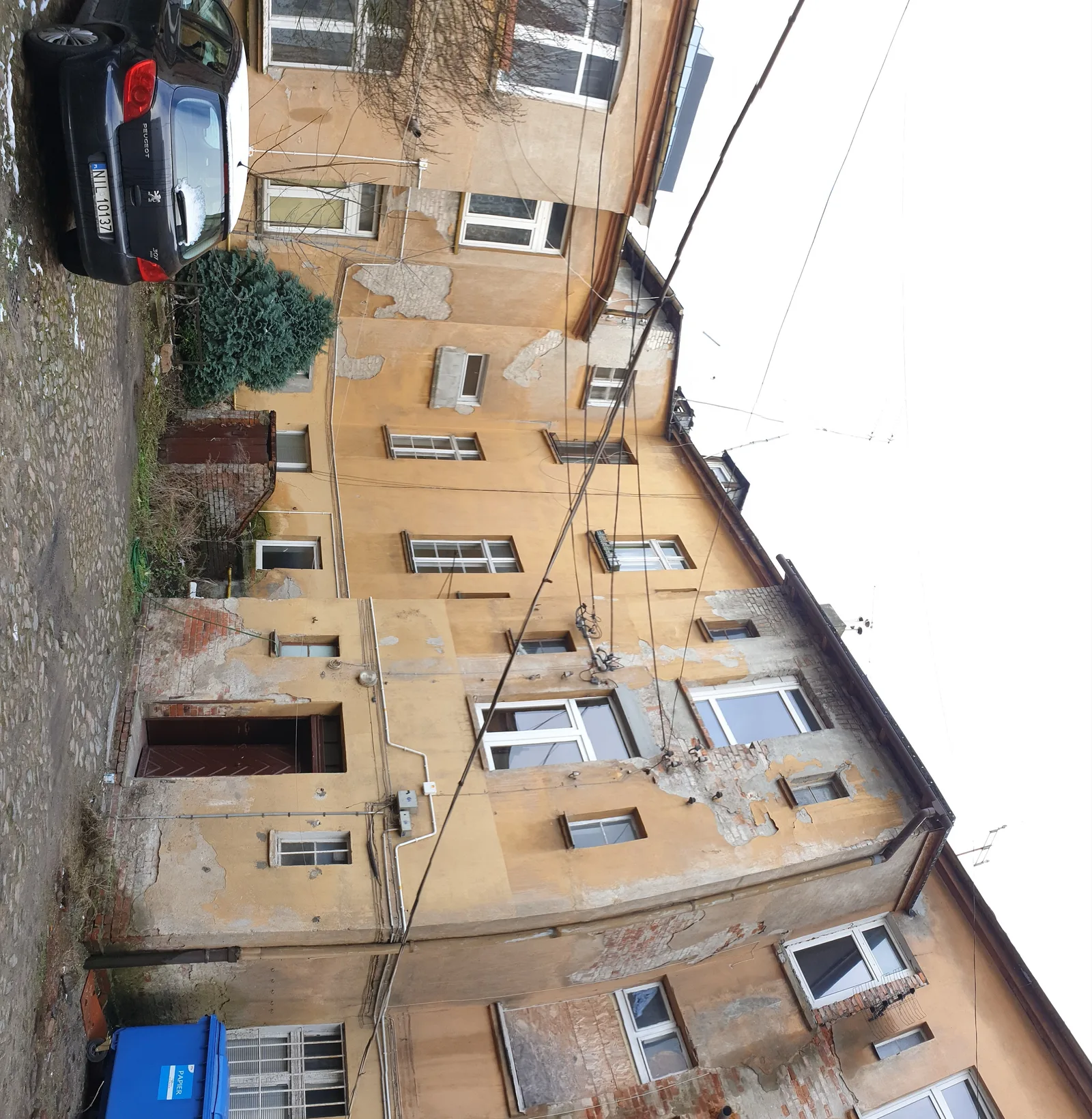 Before: heritage Fachwerk window detail with red-brown timber frame, broken glass, and exposed wall structure documenting the building condition before rehabilitation
