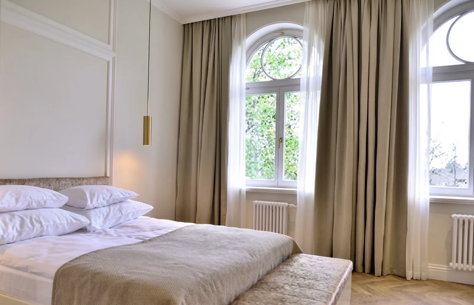 Hotel bedroom with arched windows, golden curtains, white bed, and pendant — Gemini upscale