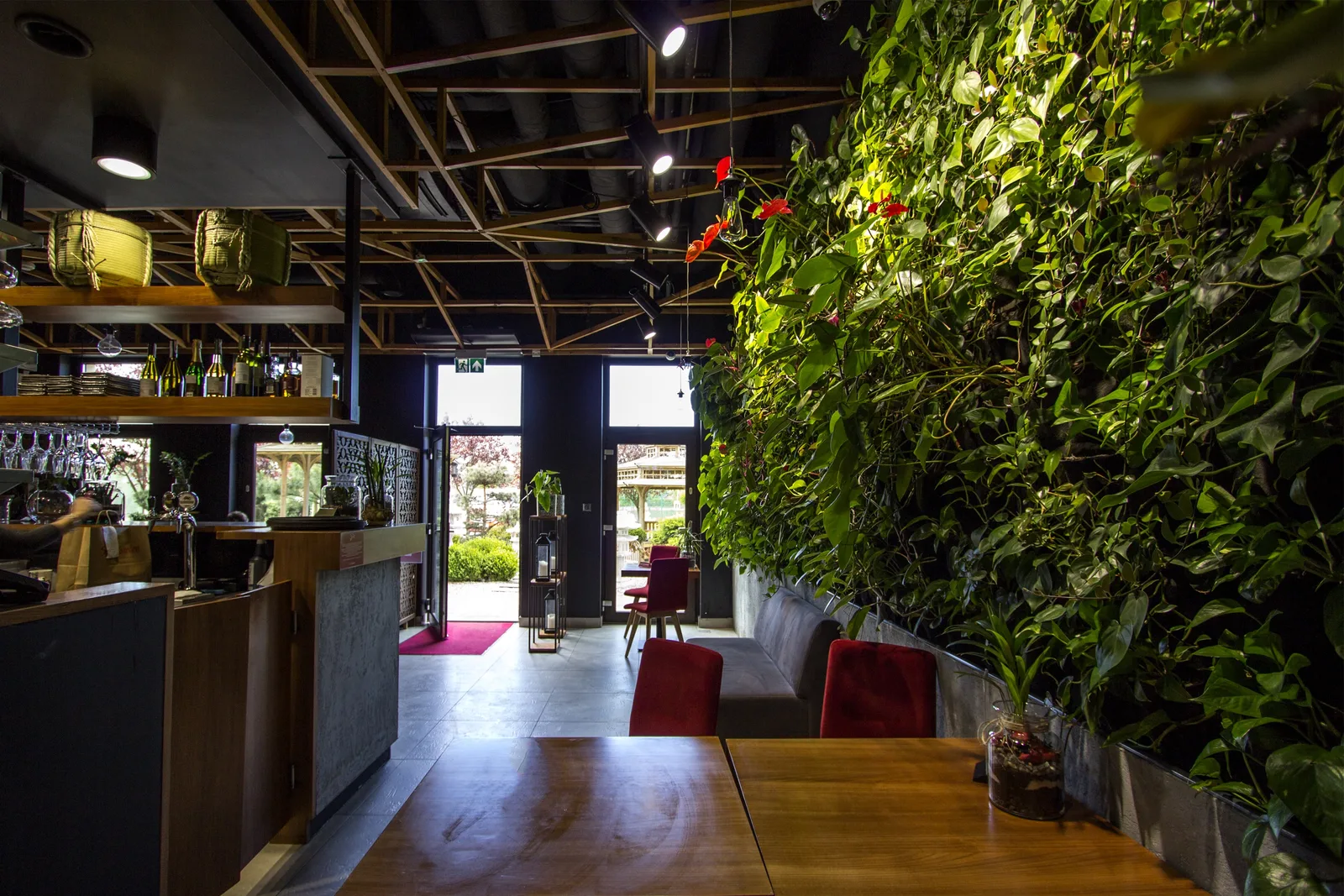 Interior: entrance and ground floor zone with green wall right, bar counter left, open doors to Japanese garden