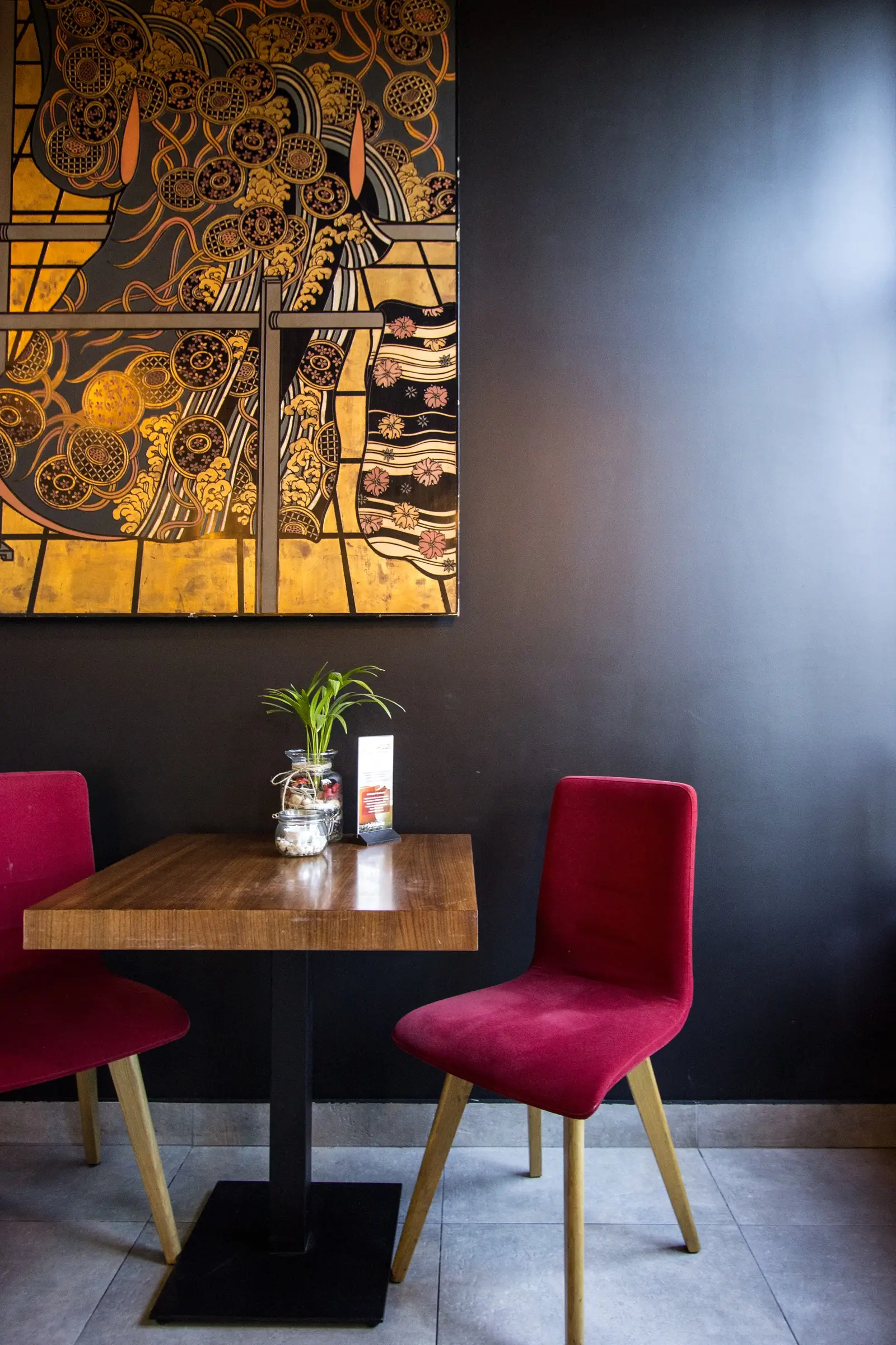 Interior: Klimt art panel close-up — gold and black Japanese motif artwork on charcoal wall, dining table below