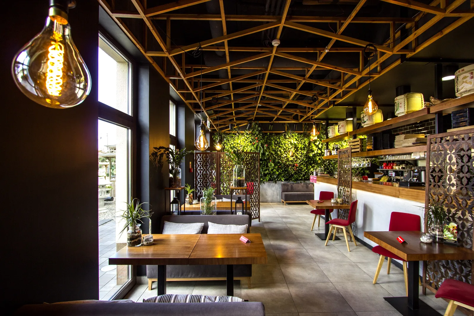 Interior: bar counter from standing height, pendant left, ceiling lattice, sake barrel shelves, staff visible