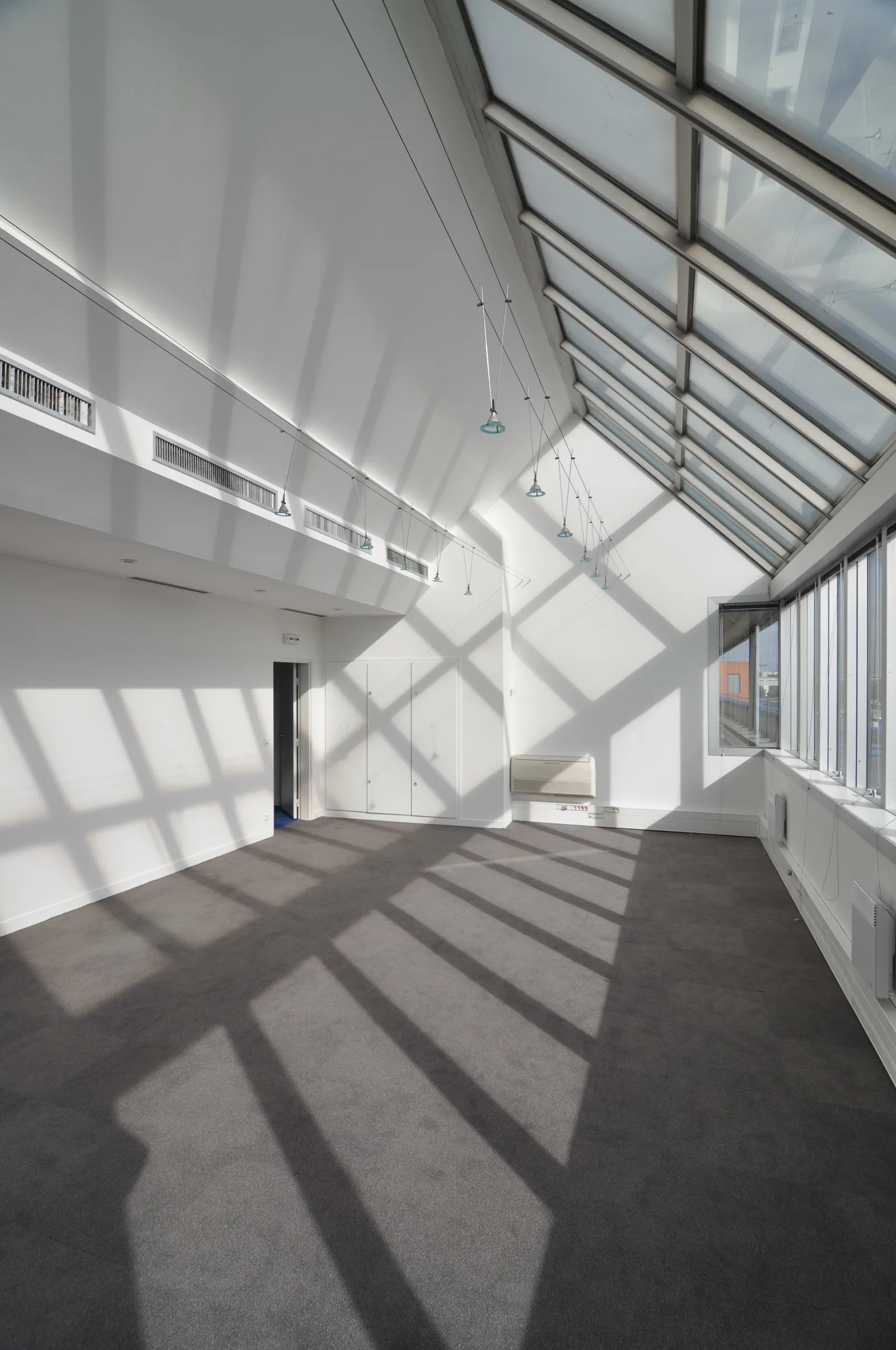Before: interior stairwell and lobby space with concrete walls, metal railings, and natural light from above showing bare existing conditions and strong linear perspective