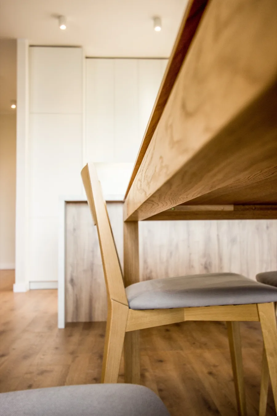 Dining decor detail with ribbed ceramic vases on oak table, forest art print, and chrome globe pendant above