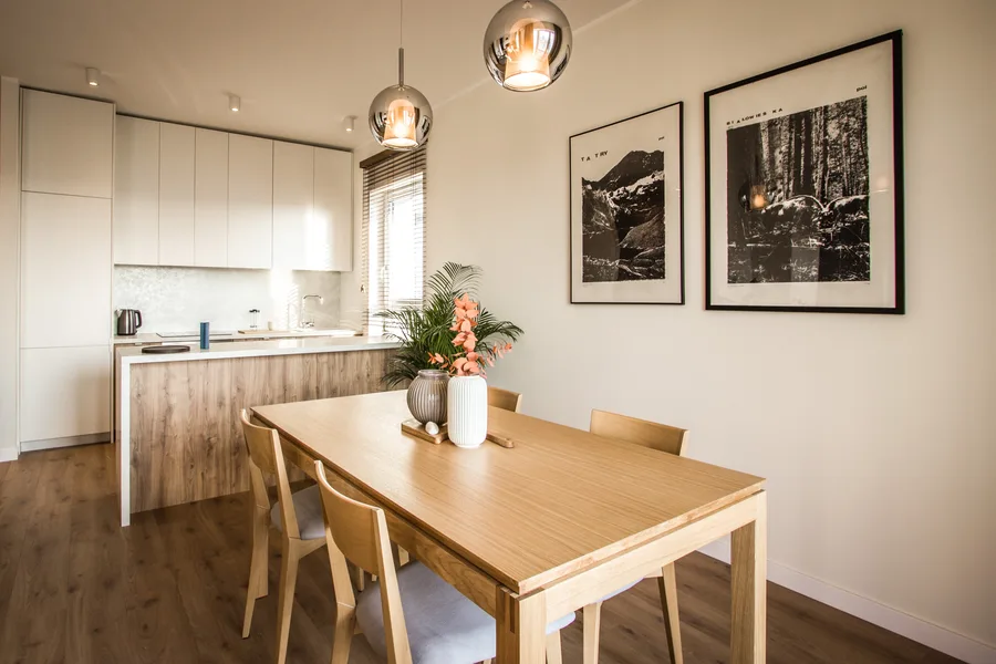 Kitchen and dining zone from entry perspective with oak island, white upper cabinets extending to ceiling, and globe pendant cluster