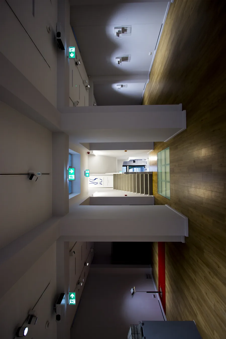 Interior: multi-level view with red accent elements showing vertical gallery connections within the heritage 1890 industrial shell of the former municipal slaughterhouse building