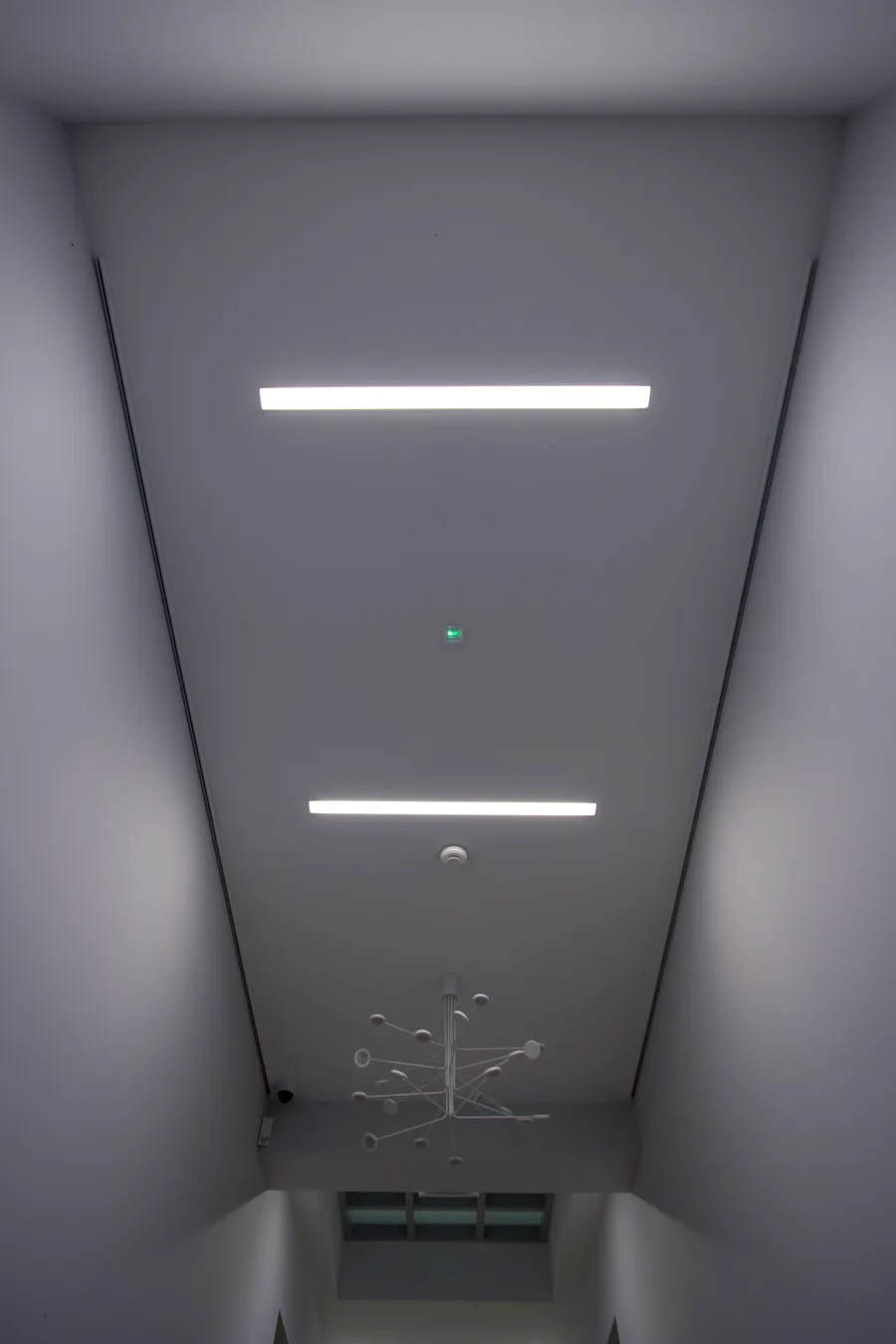 Interior: stairwell with molecular-atom-shaped sculptural light fixture suspended in the heritage circulation space, showing spherical metal nodes along horizontal white rails