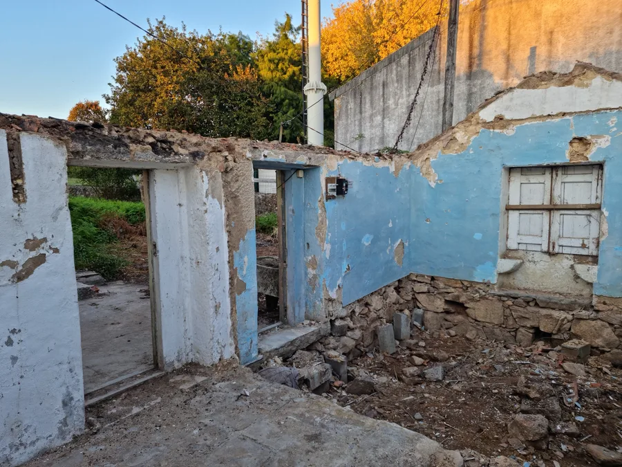 Construction: blue room discovery photo during October 2021 demolition showing vivid blue painted walls revealed behind plaster, shuttered window, granite rubble, and golden autumn tree outside